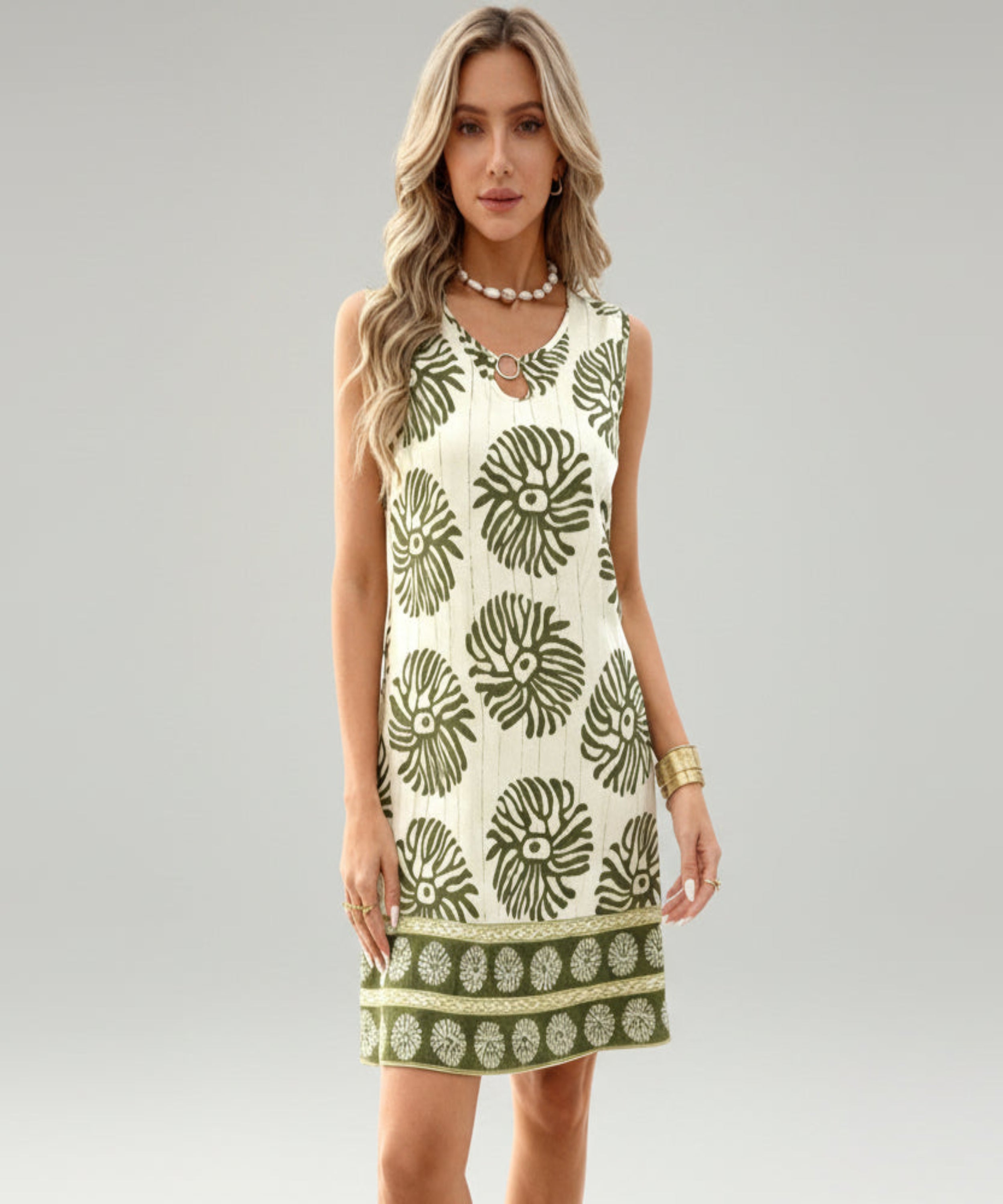 Woman wearing a sleeveless dress with green floral pattern on a white background