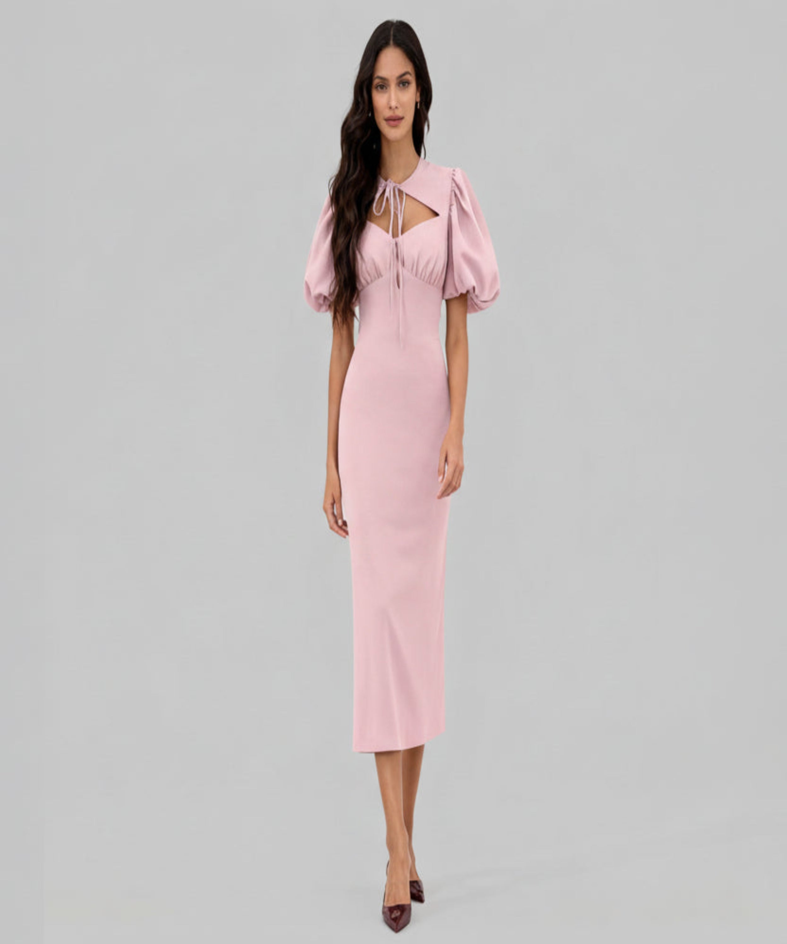 Woman wearing a pink dress with puff sleeves on a white background