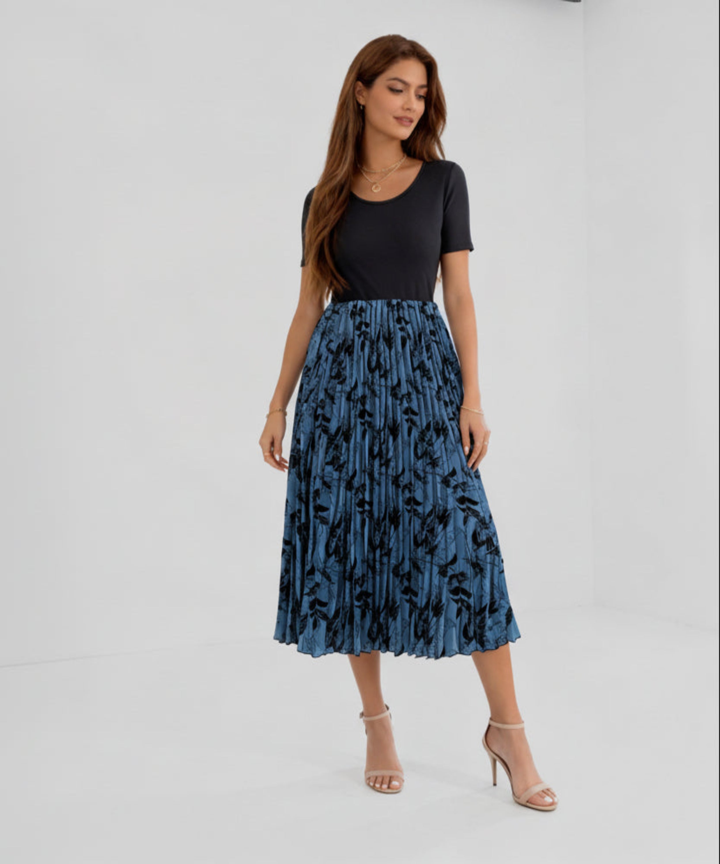 Woman wearing a black top and blue floral skirt on a white background