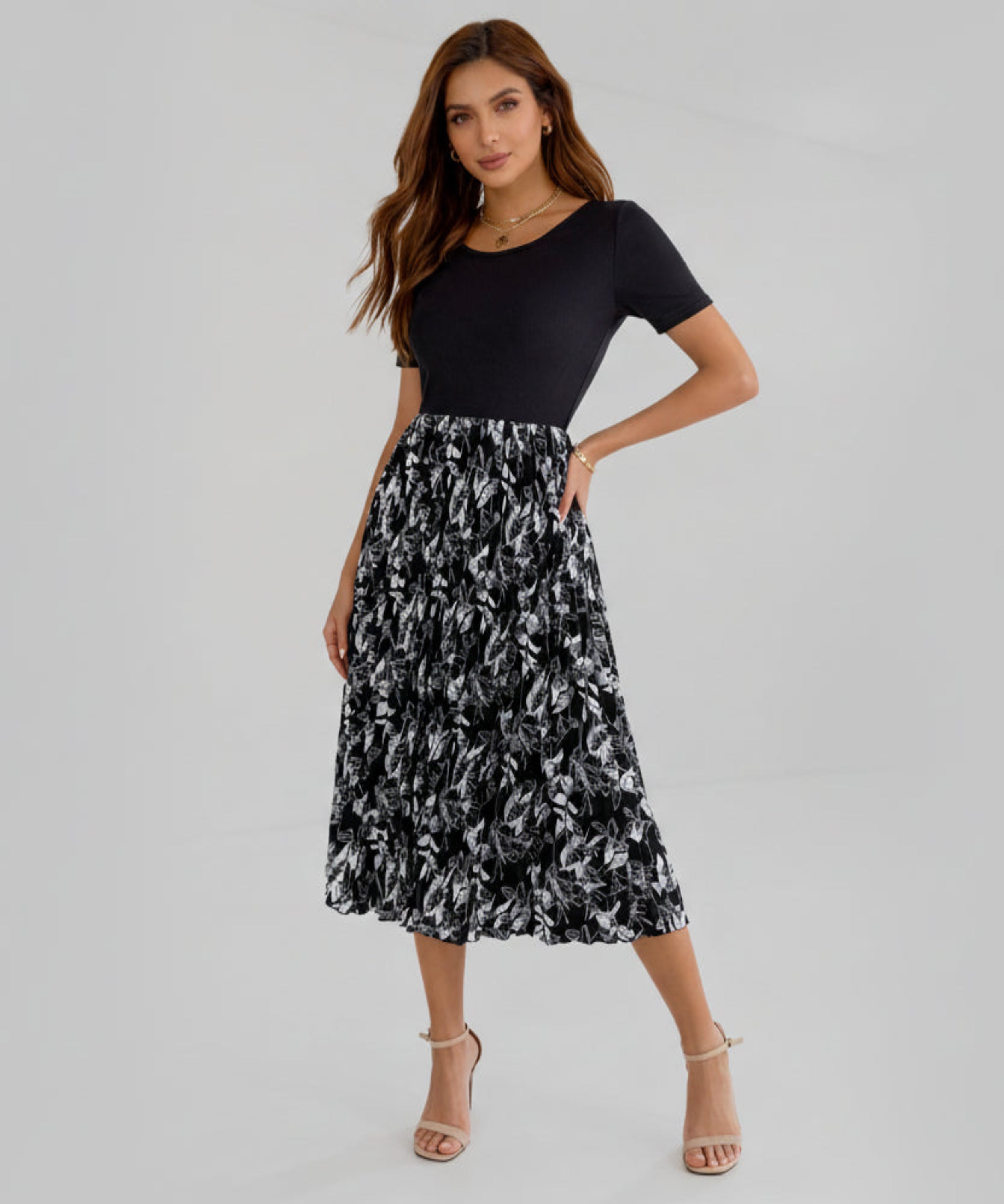 Woman wearing a black top and black and white floral skirt on a white background