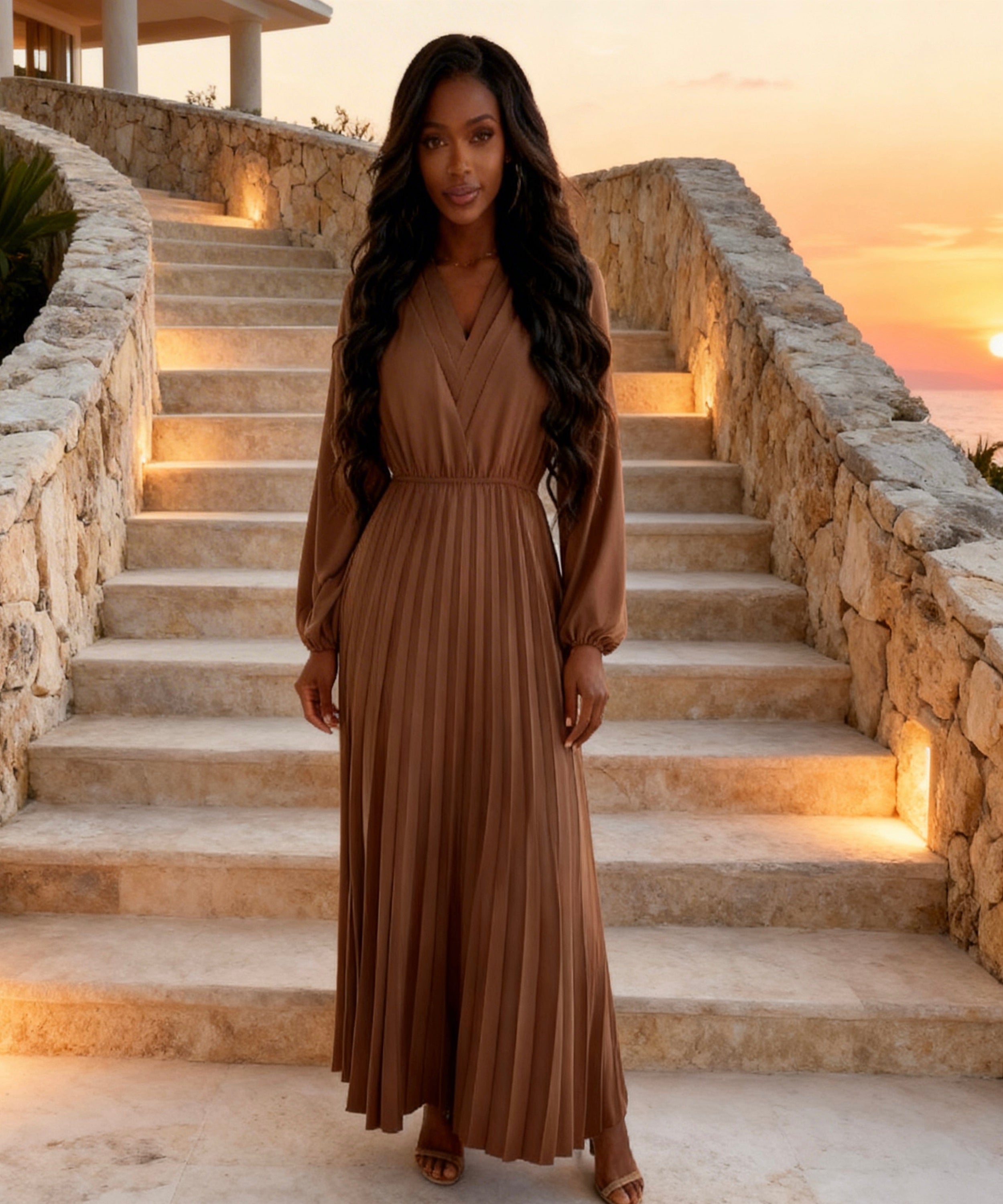 Woman in a brown dress standing on stone steps with a sunset in the background
