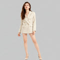 Woman wearing a beige blazer and shorts on a white background