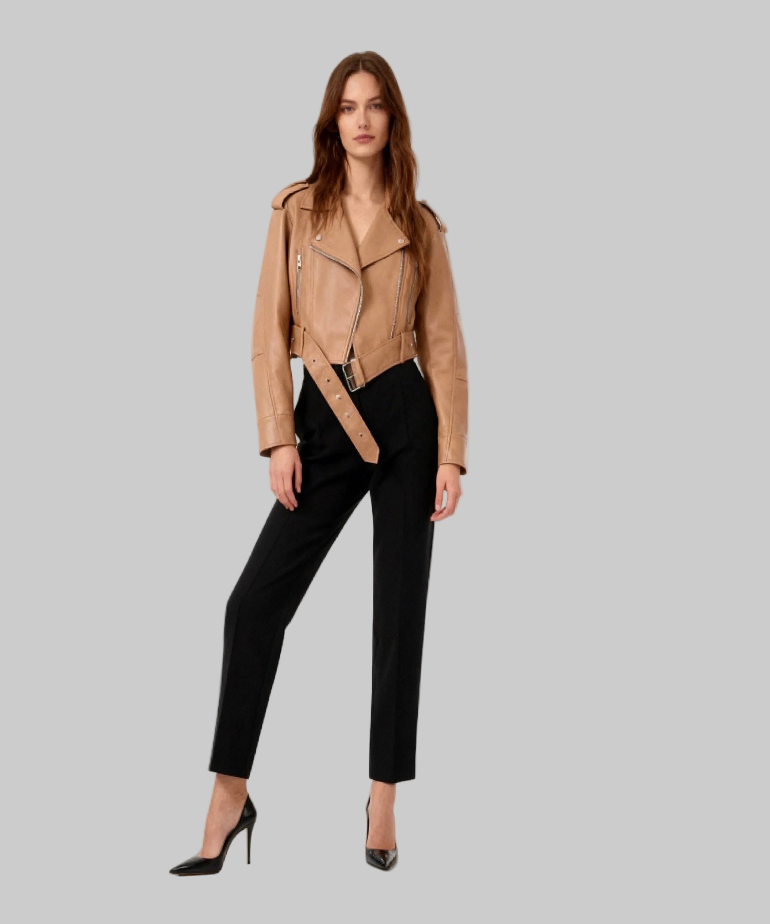 Woman wearing a tan leather jacket and black pants on a white background
