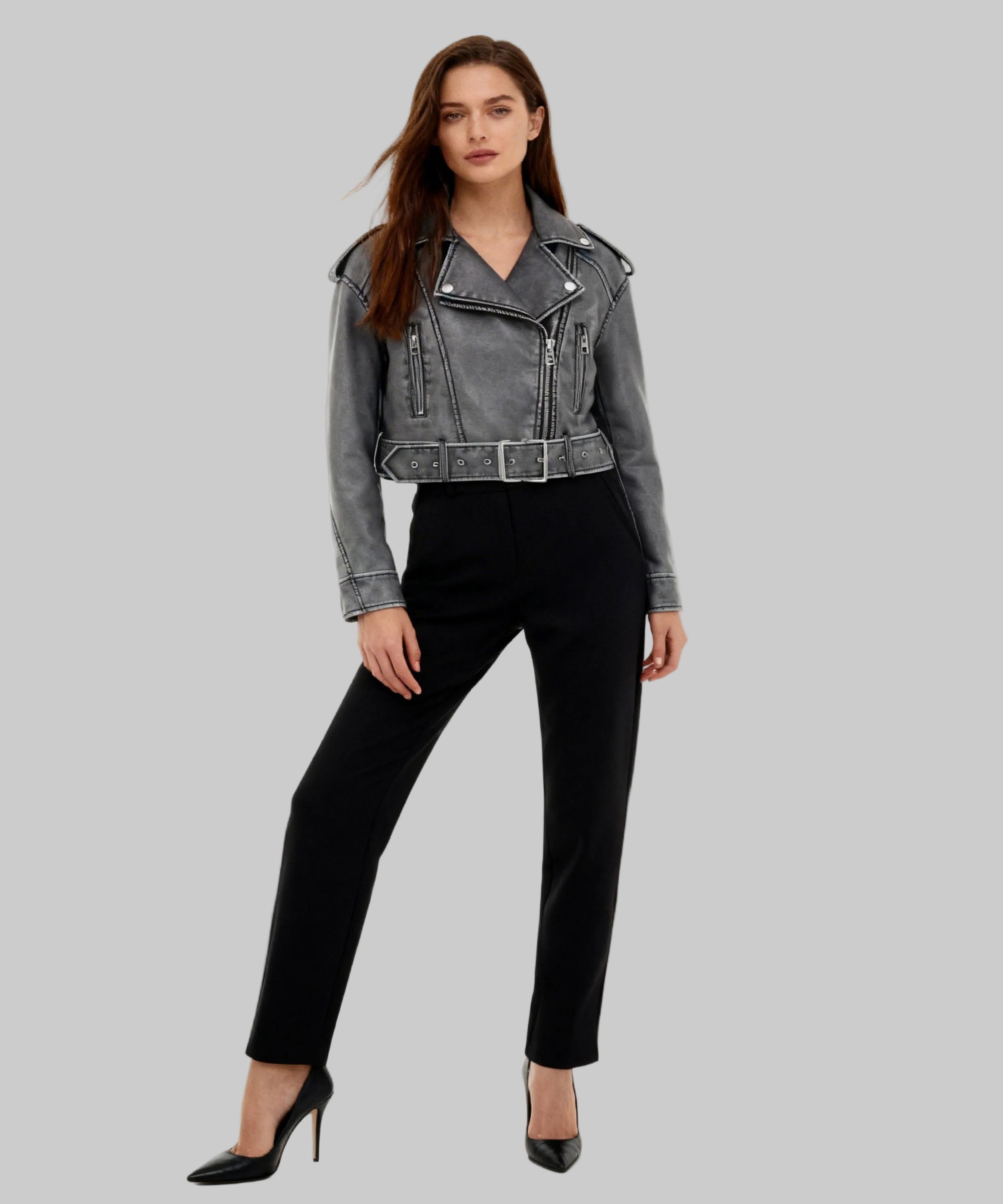 Woman wearing a gray denim jacket and black pants on a white background