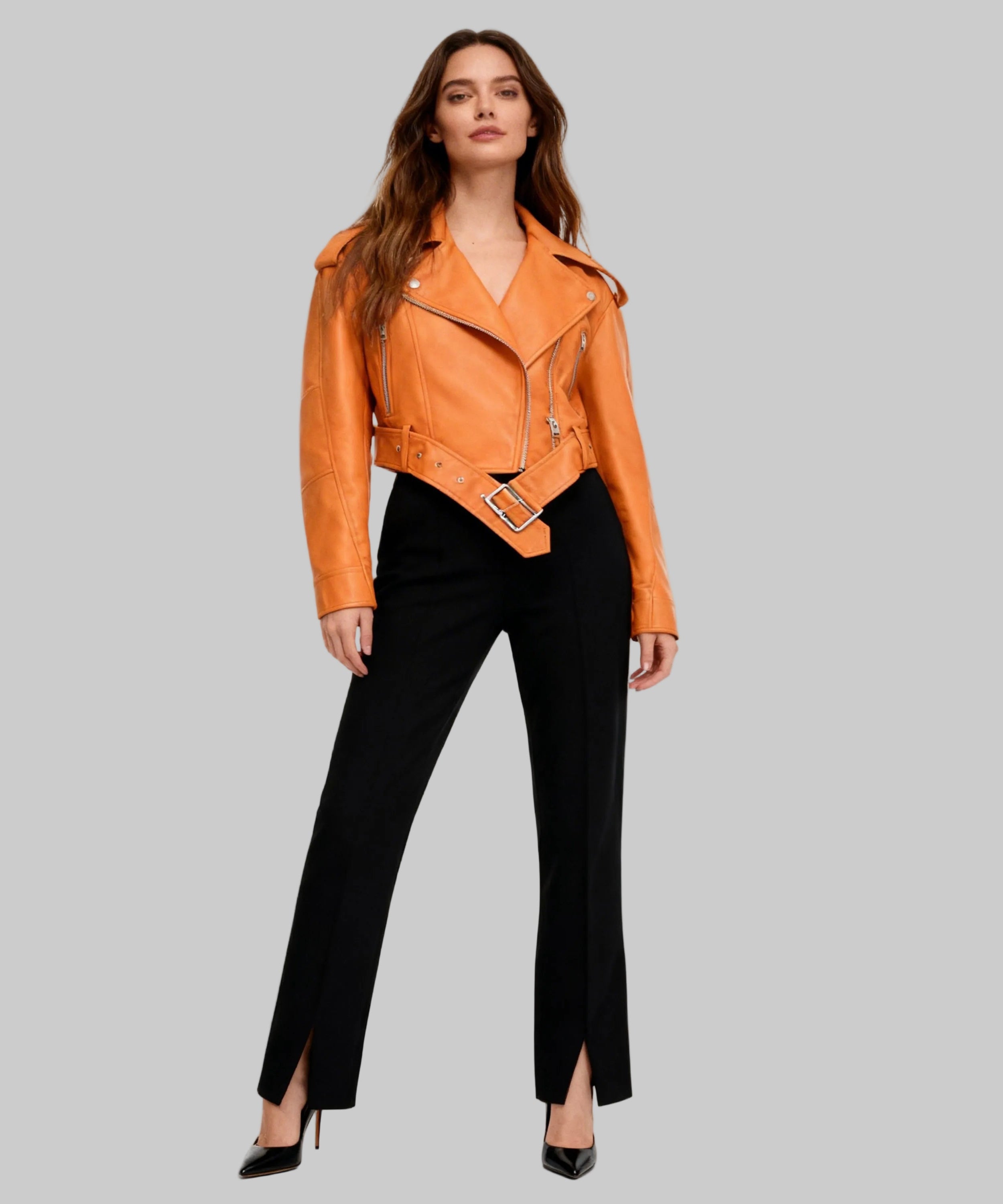 Woman wearing a tan leather jacket and black pants on a white background