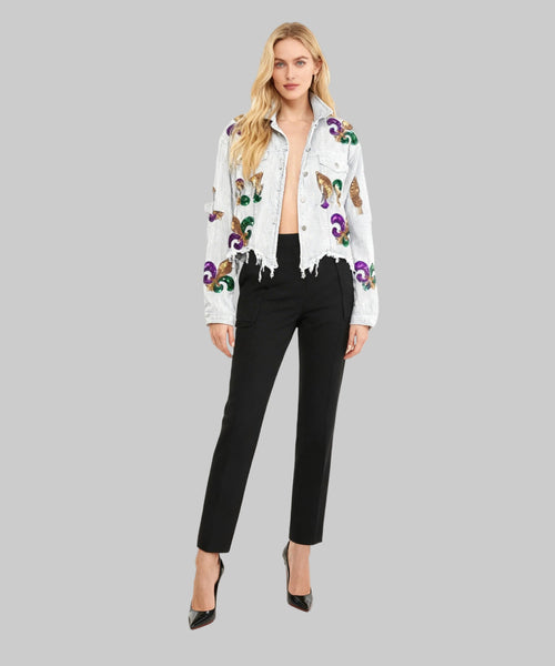 Woman wearing a white embroidered jacket and black pants on a white background