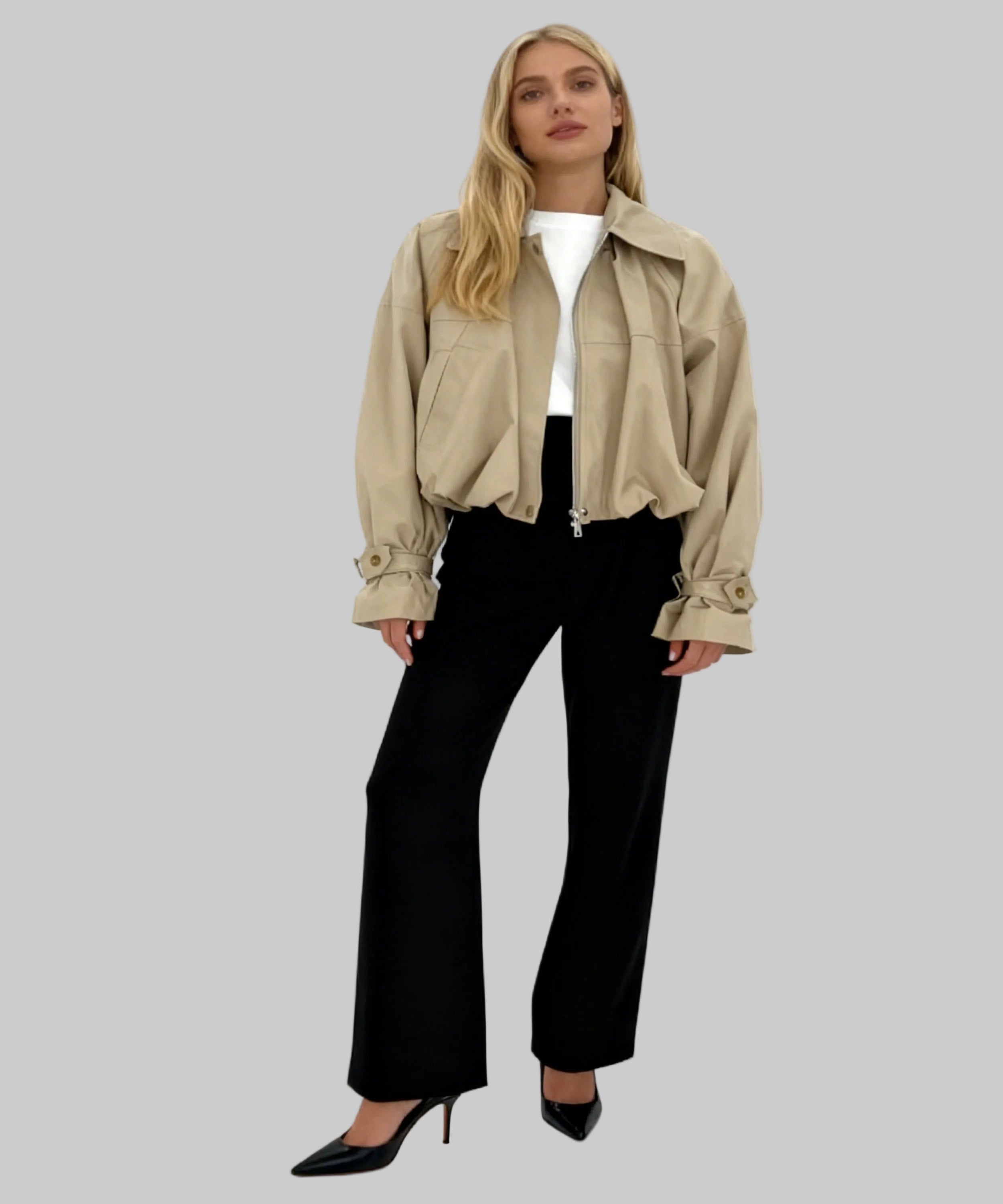 Woman wearing a beige jacket and black pants on a white background