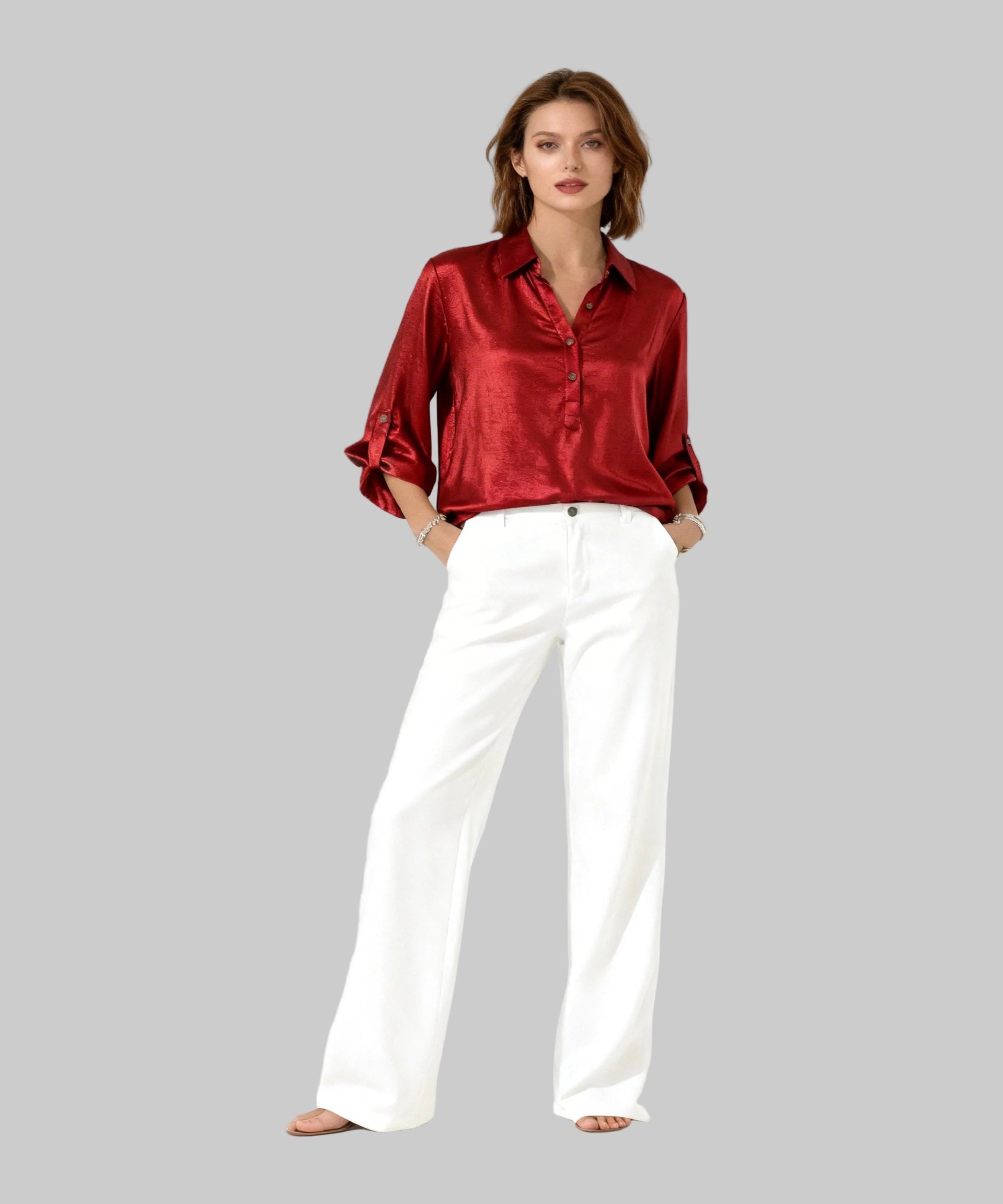 Woman wearing a red satin shirt and white pants on a white background