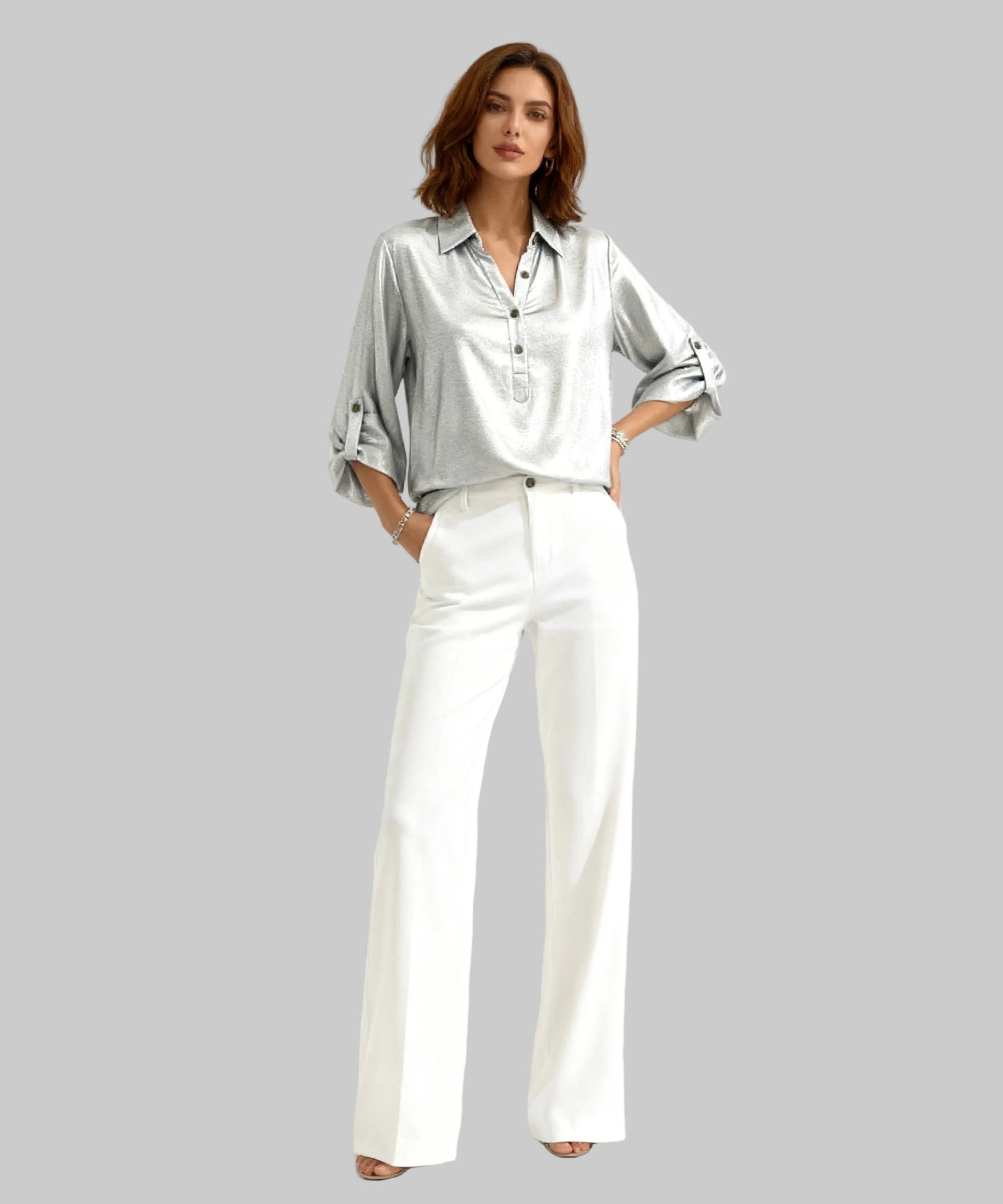 Woman wearing a silver satin shirt and white pants on a white background