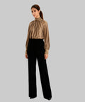 Woman wearing a beige blouse and black pants on a white background