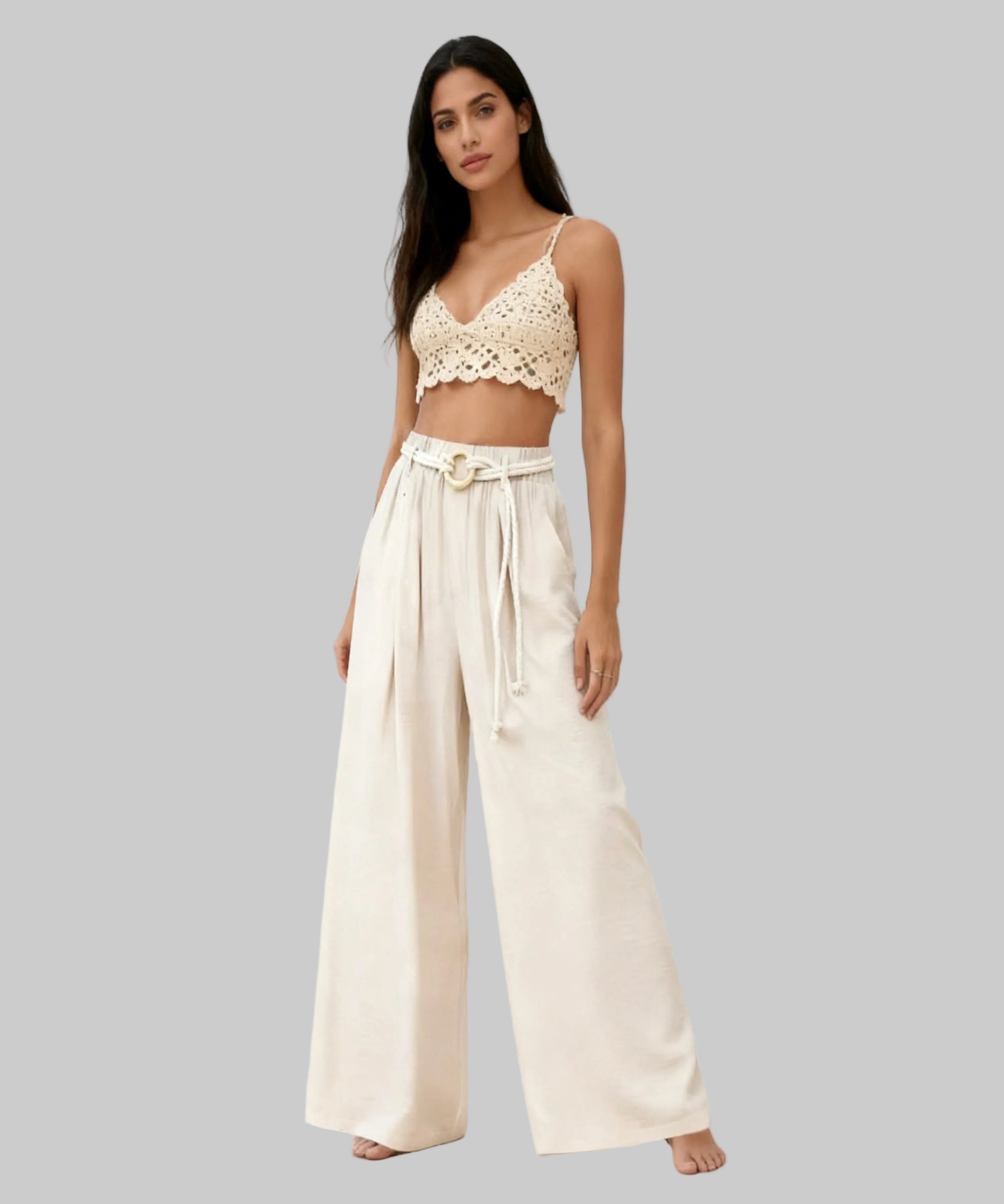 Woman wearing a beige lace top and wide-leg pants on a white background