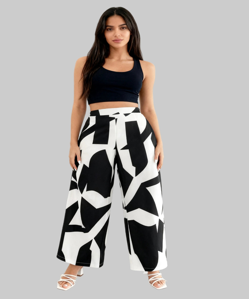 Woman wearing a black sports bra and wide-leg pants with a geometric pattern on a white background