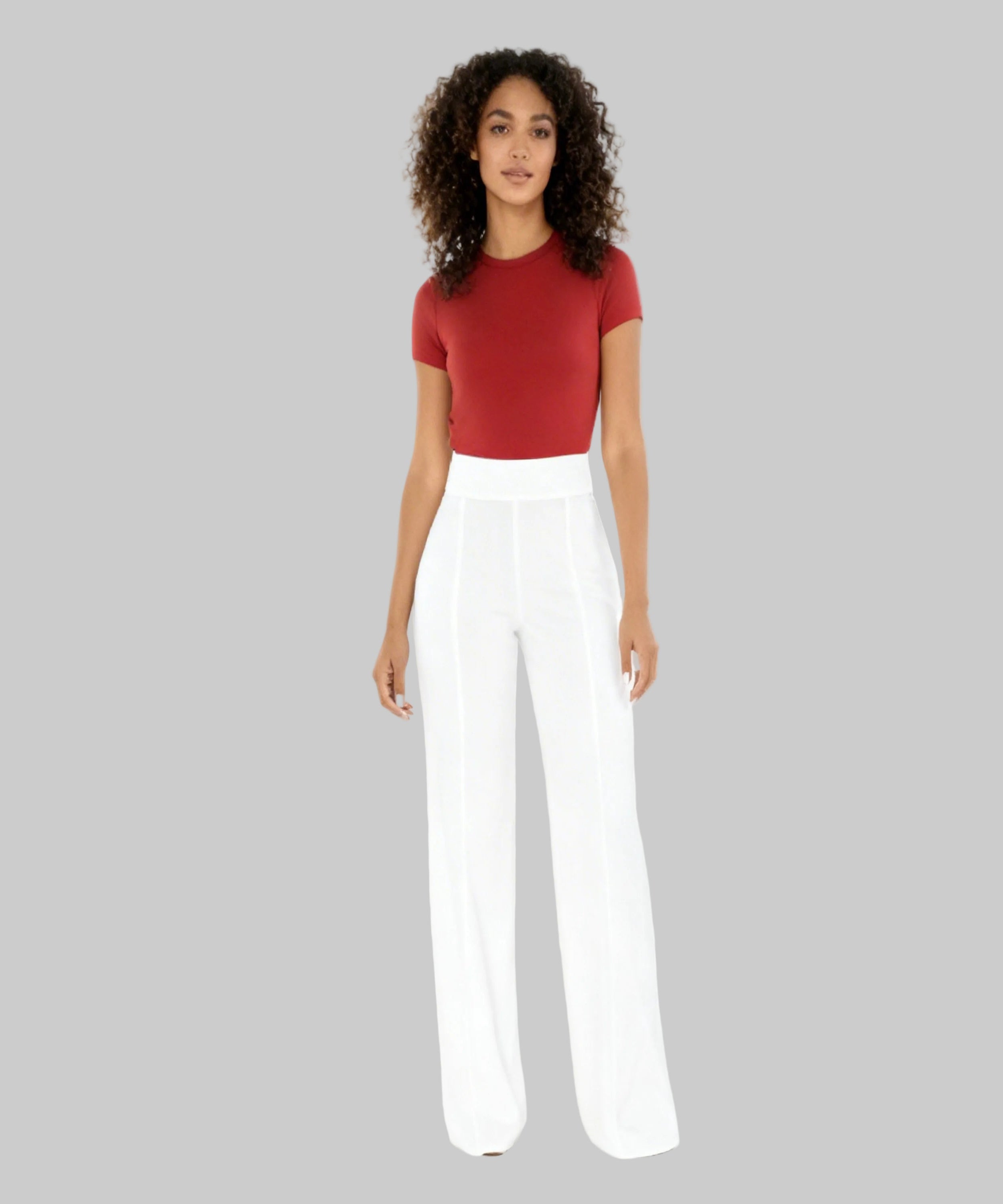 Woman wearing a red top and white pants on a white background