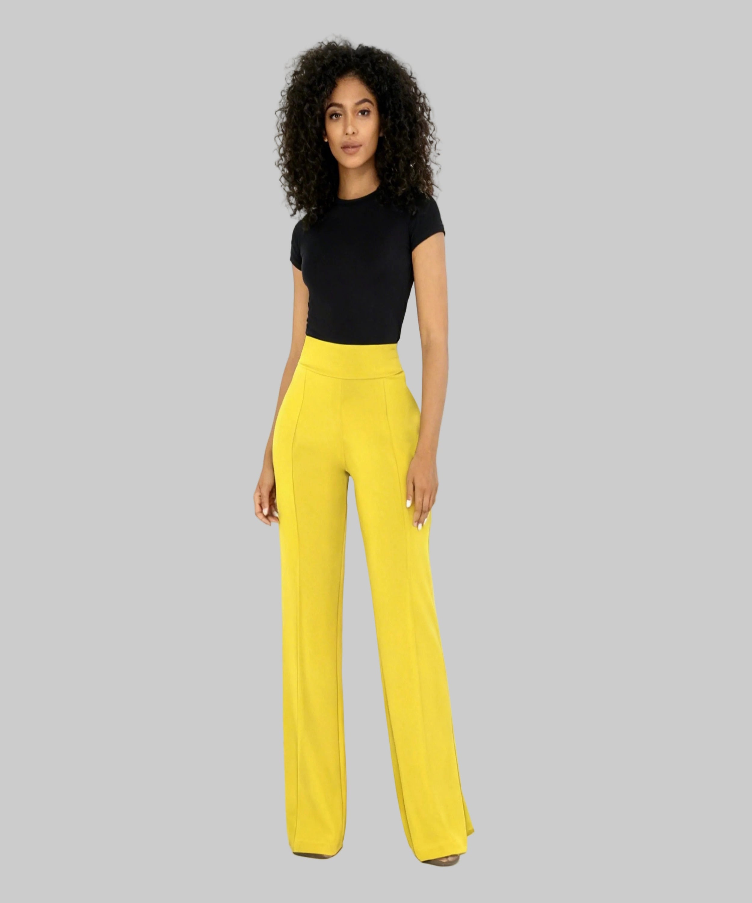 Woman wearing a black top and yellow pants on a white background