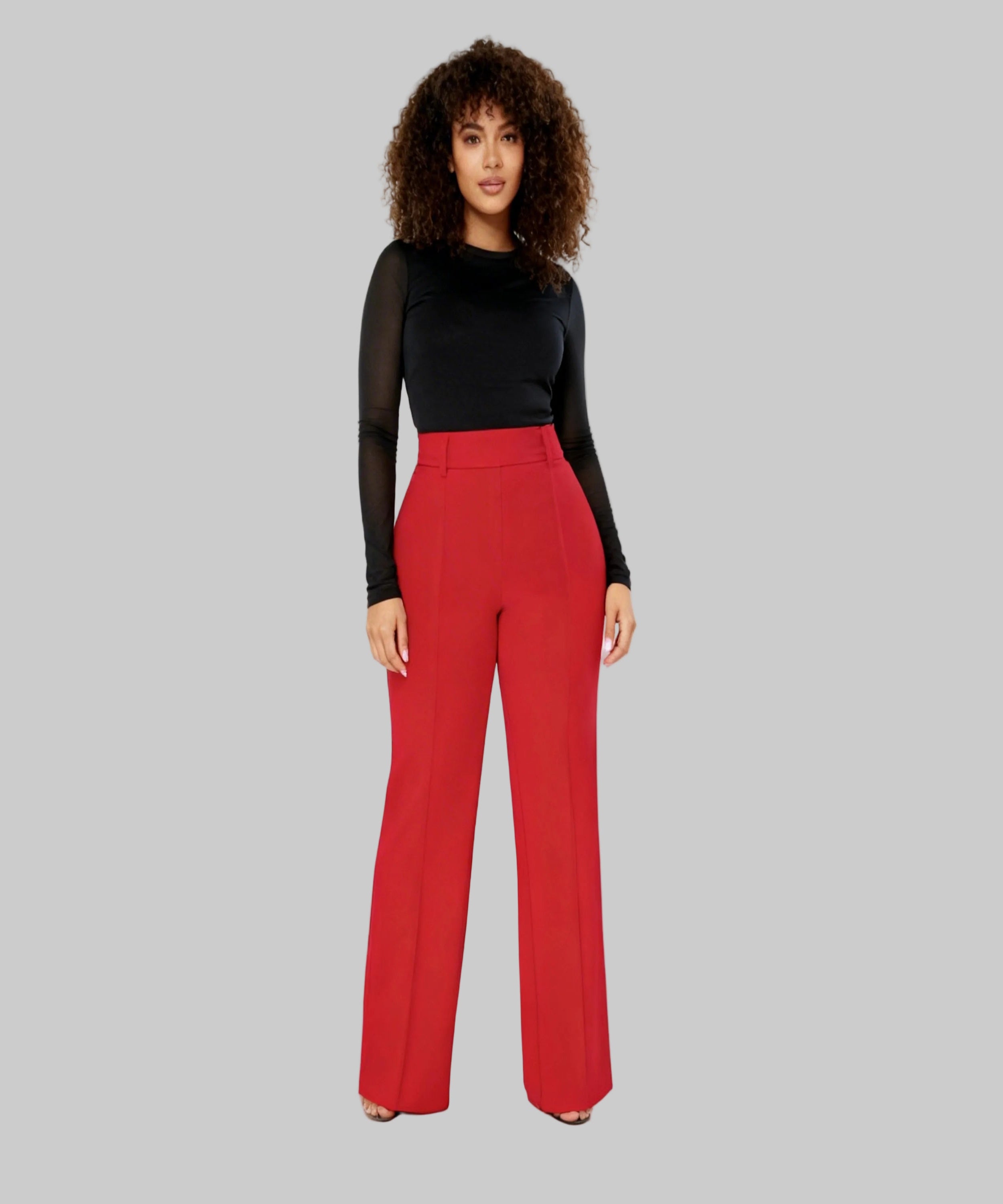 Woman wearing a black top and red pants on a white background