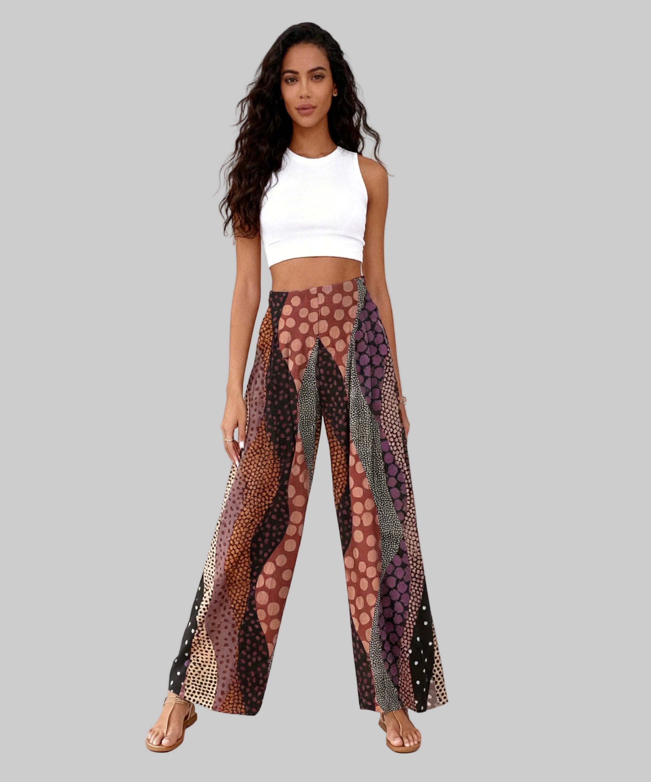 Woman wearing a white top and patterned pants on a white background