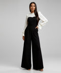 Woman wearing a black jumpsuit with a white top and sleeves on a white background