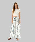 Woman wearing a white crop top and floral wide-leg pants on a white background