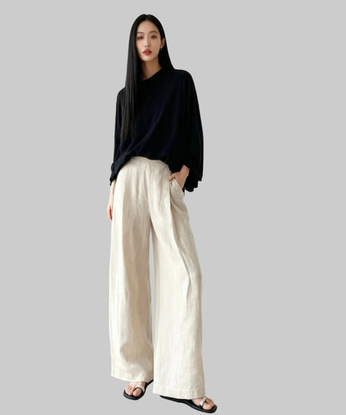 Person wearing a black top and beige wide-leg pants on a white background
