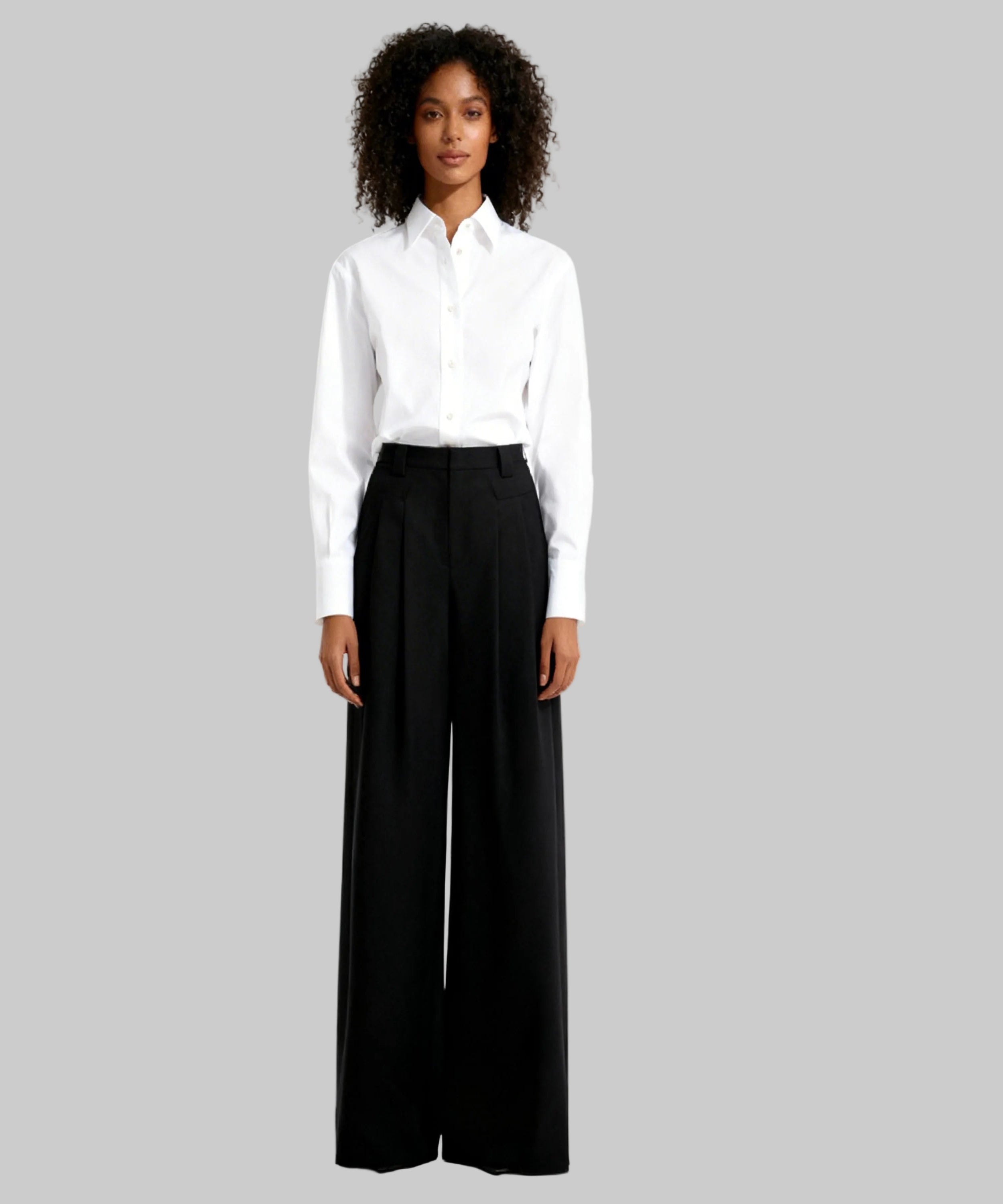 Woman wearing a white shirt and black wide-leg pants on a white background