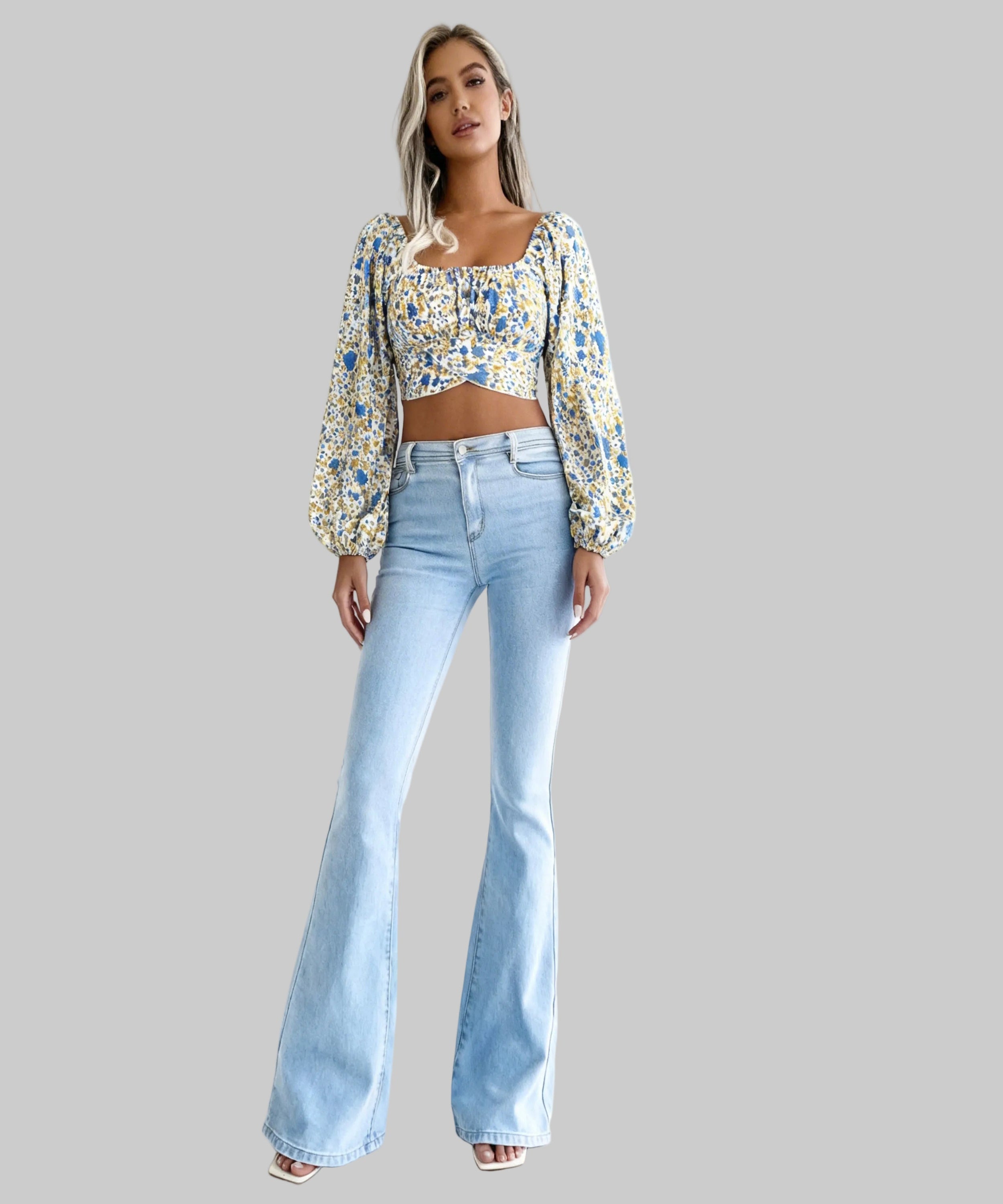 Woman wearing a floral top and light blue jeans on a white background