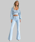 Woman wearing a floral top and light blue flared jeans on a white background