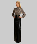 Woman wearing a leopard print blouse and black pants on a white background
