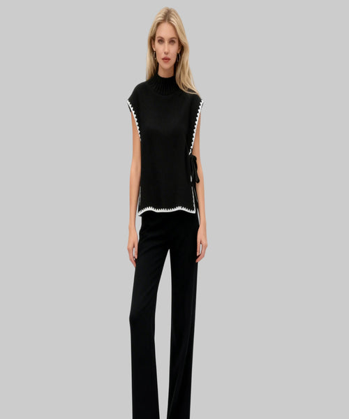 Woman wearing a black outfit with white trim on a white background