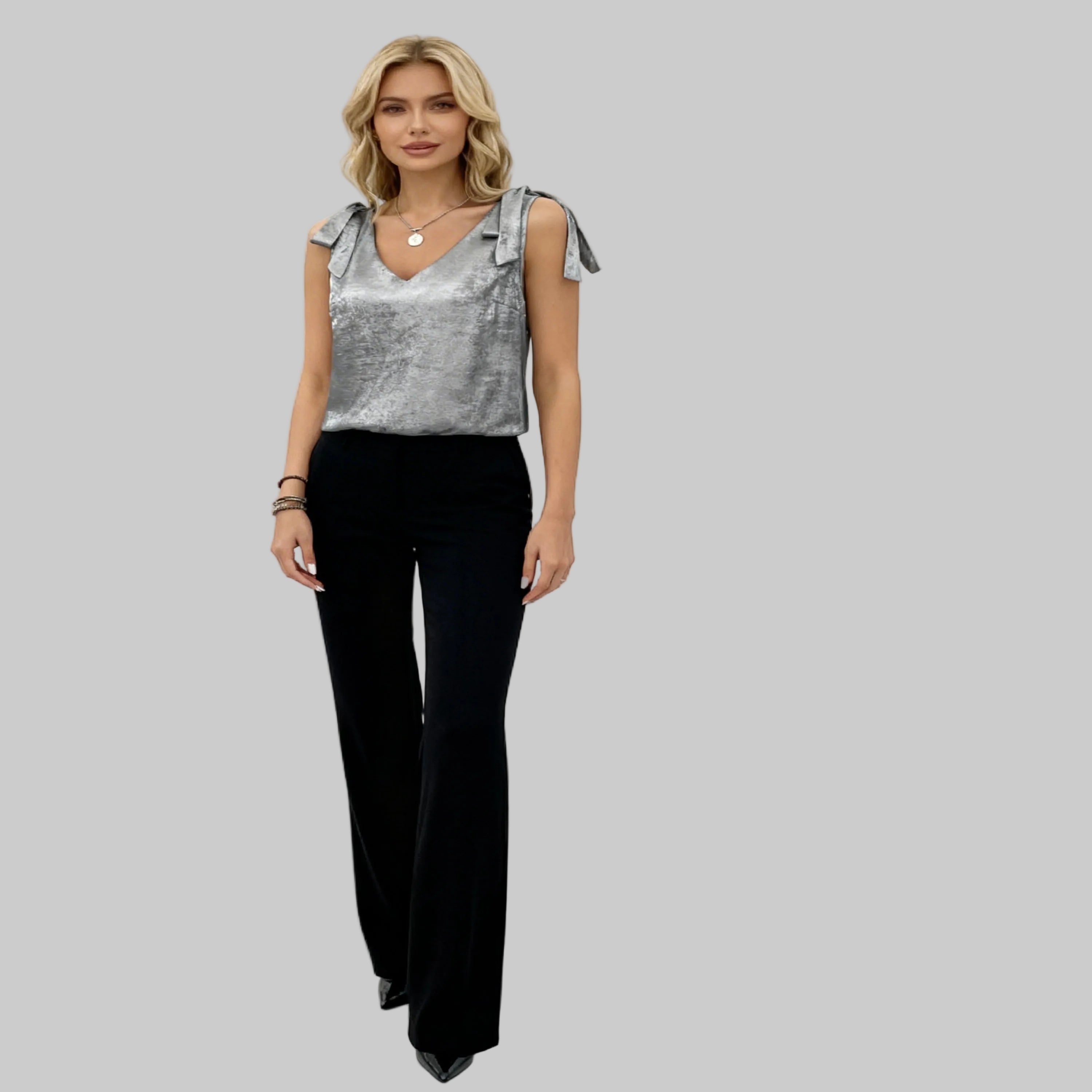 Woman wearing a silver top with ruffle shoulders and black pants on a white background