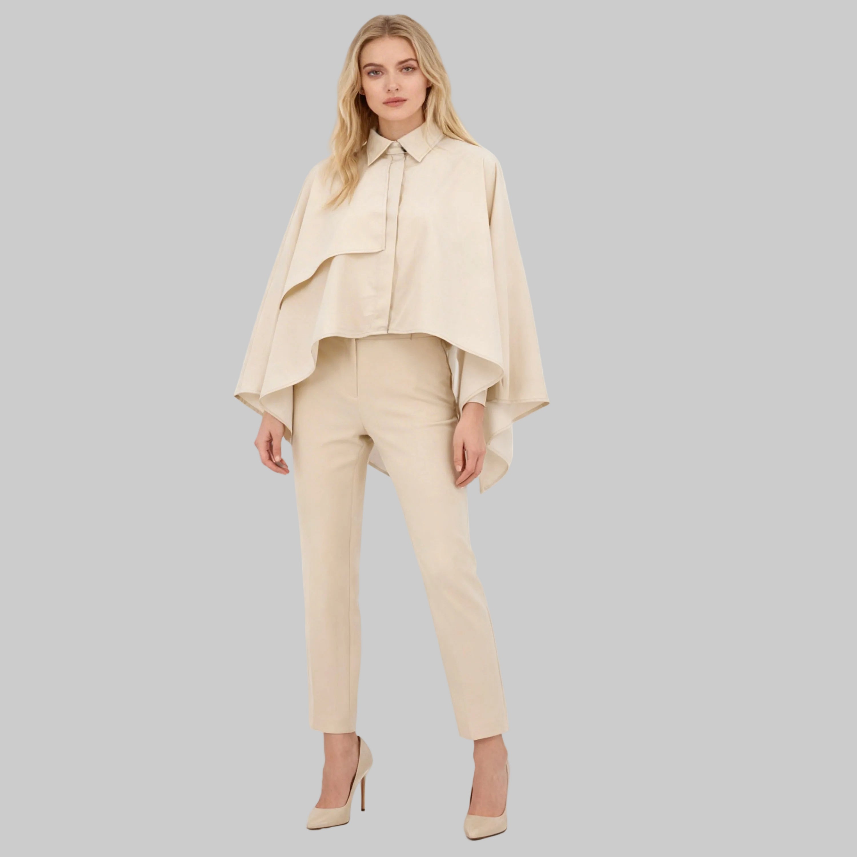 Woman wearing a beige outfit with a cape on a white background