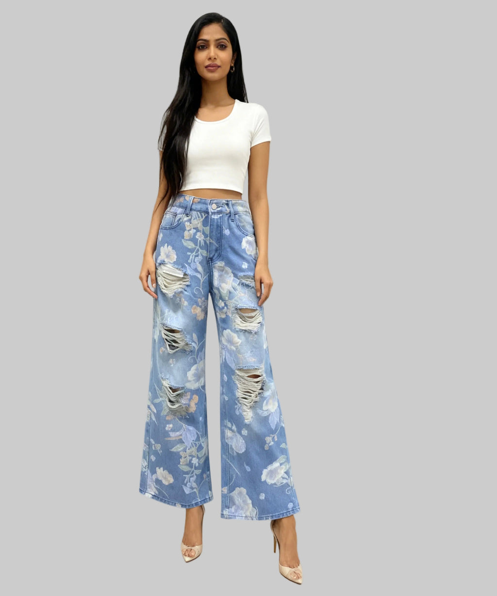 Woman wearing a white top and blue floral wide-leg pants on a white background