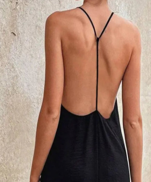 Black dress with open back worn by a person on a neutral background