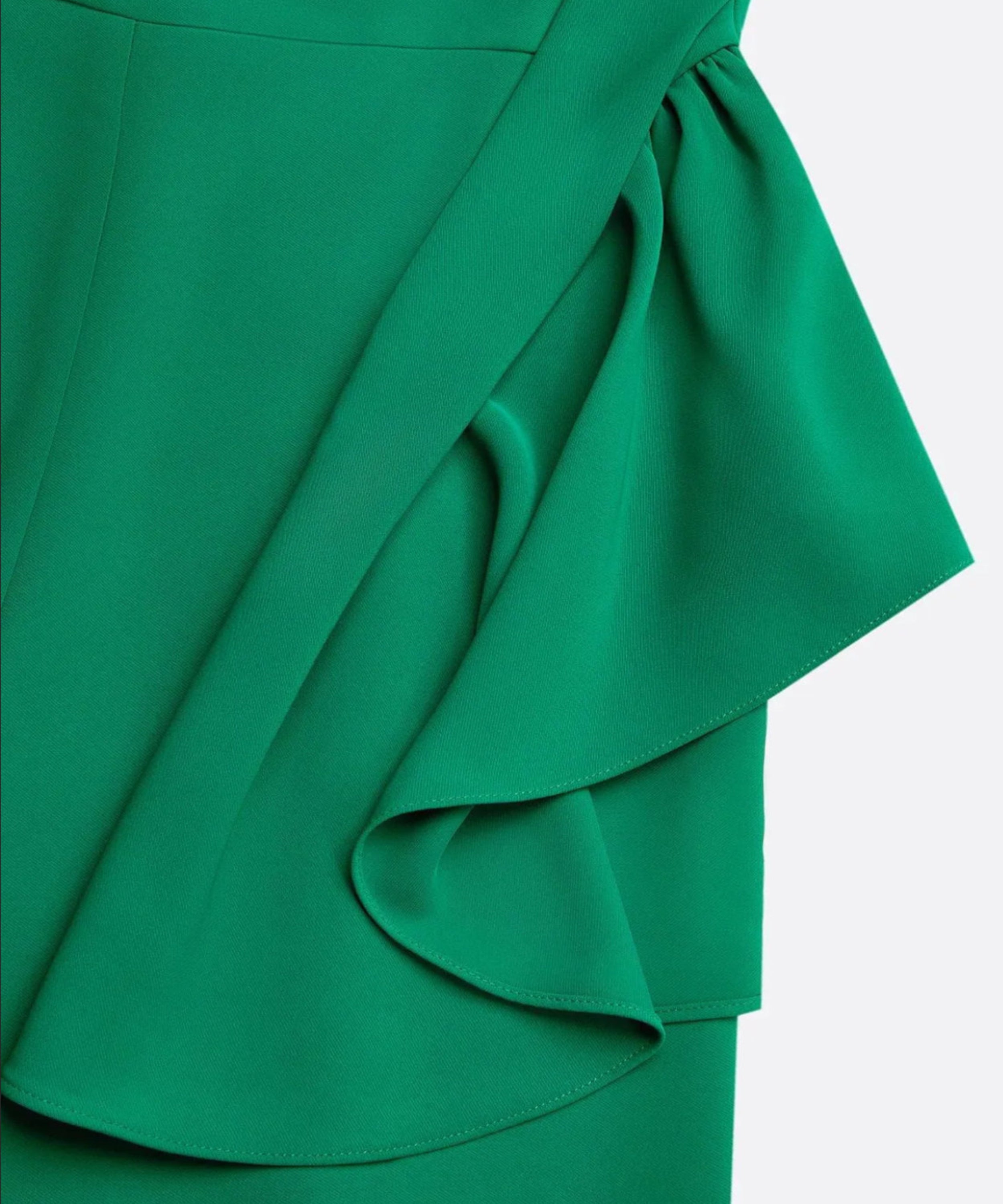Close-up of a green dress with ruffled detail on a white background