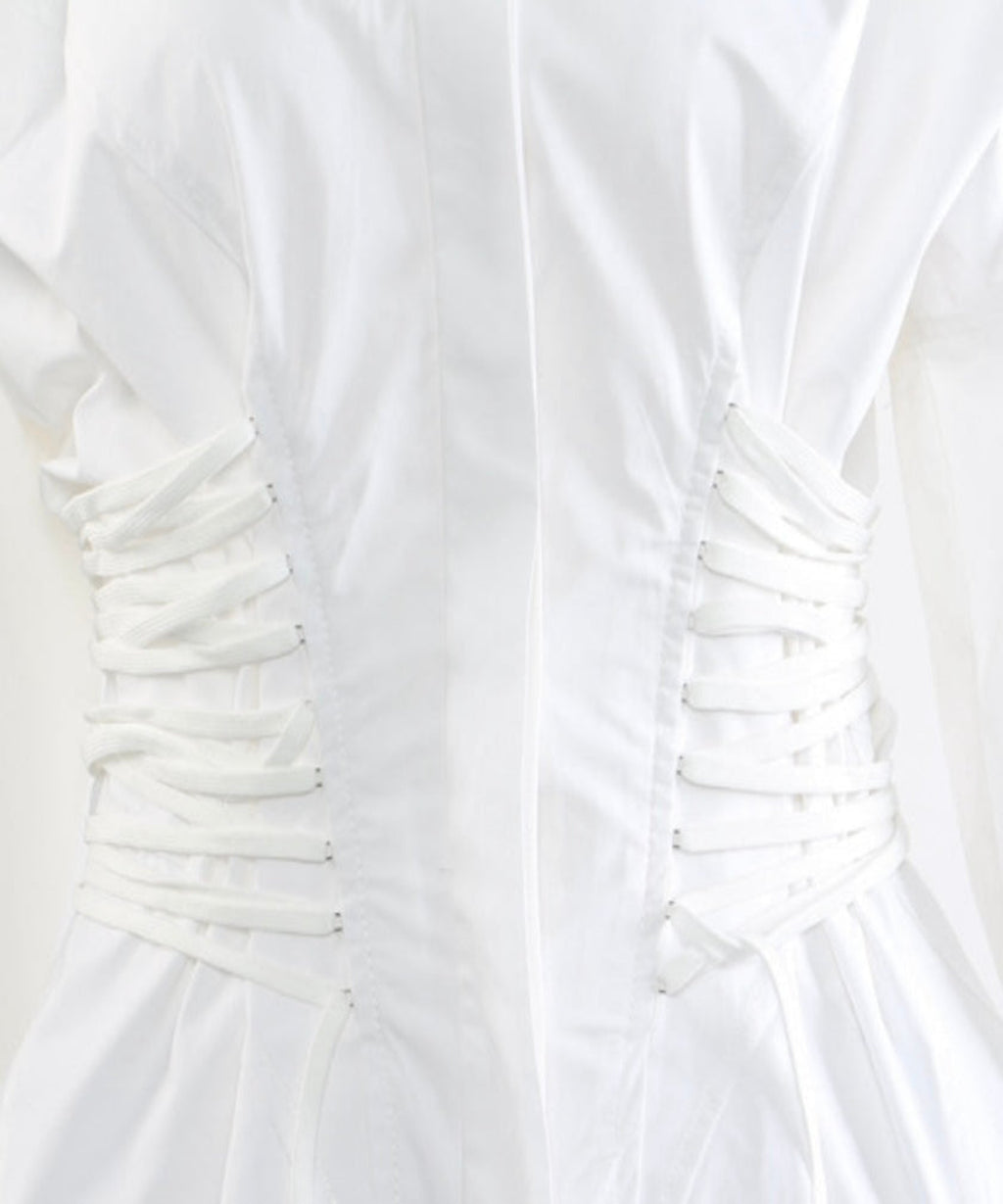 Close-up of a white dress with ruched bodice on a light gray background