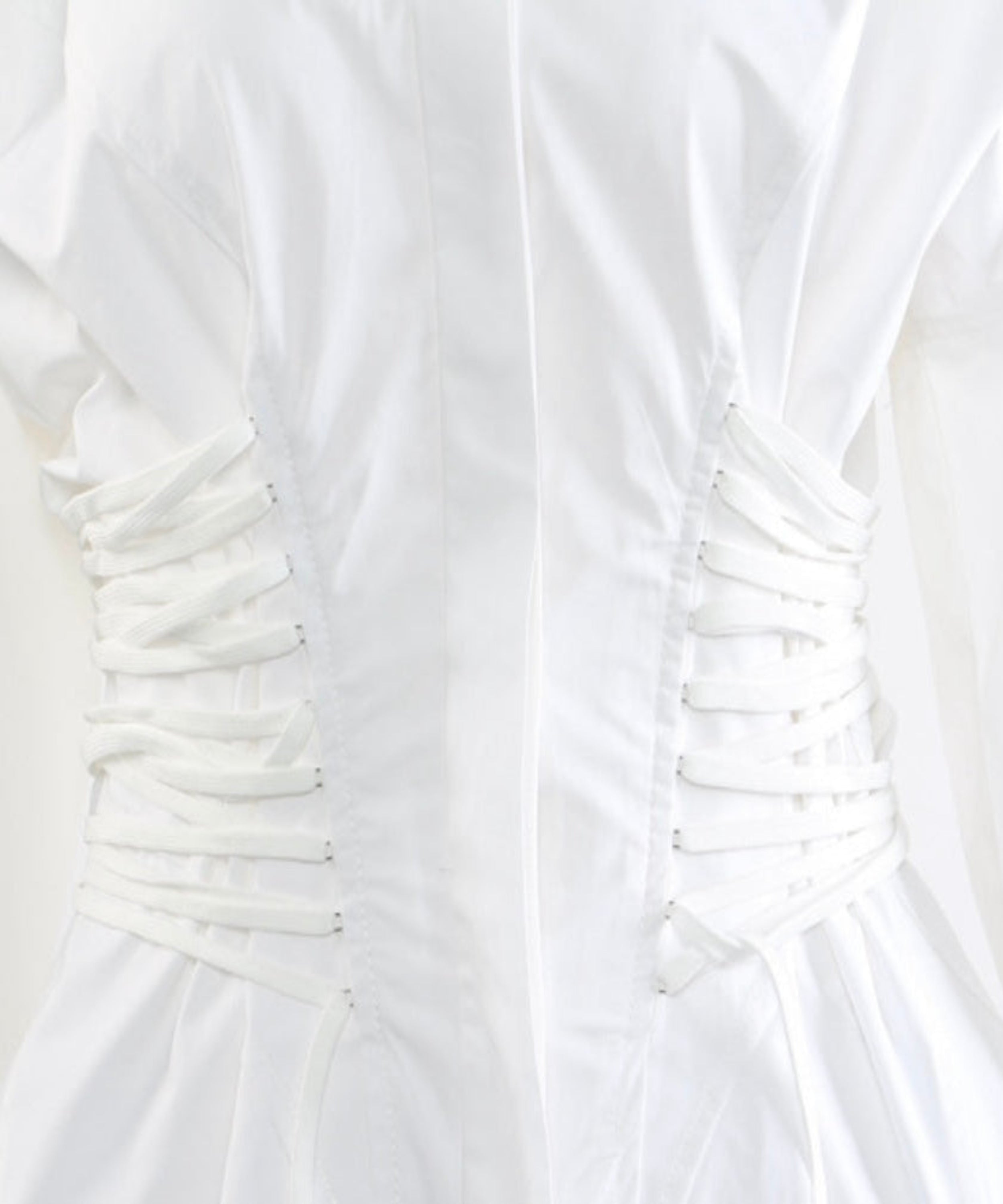 Close-up of a white dress with ruched bodice on a light gray background