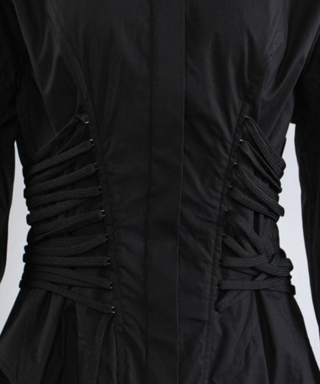 Close-up of a black dress with ruched back on a light gray background
