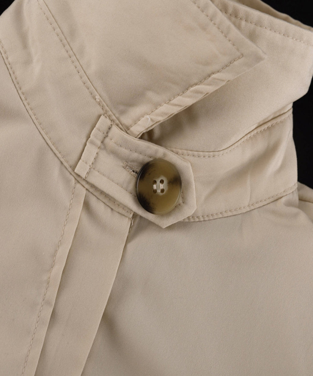 Close-up of a beige button on a jacket with a black background