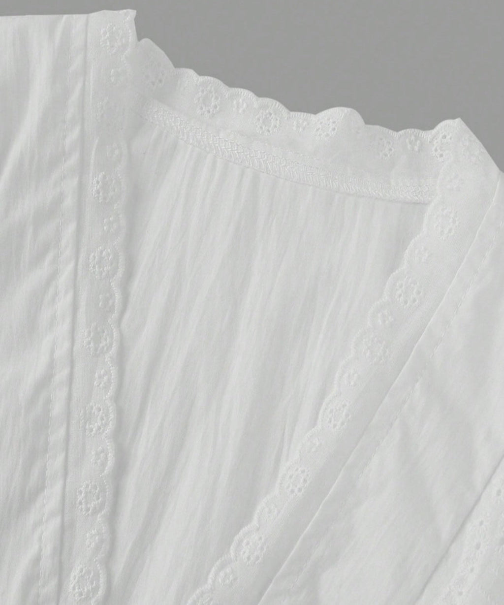 Close-up of a white textured fabric with lace detailing on a gray background