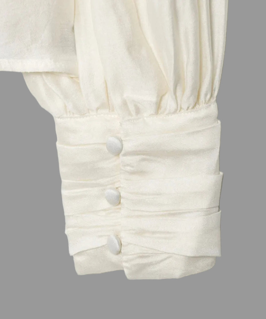 Close-up of a white blouse with buttons on a light gray background