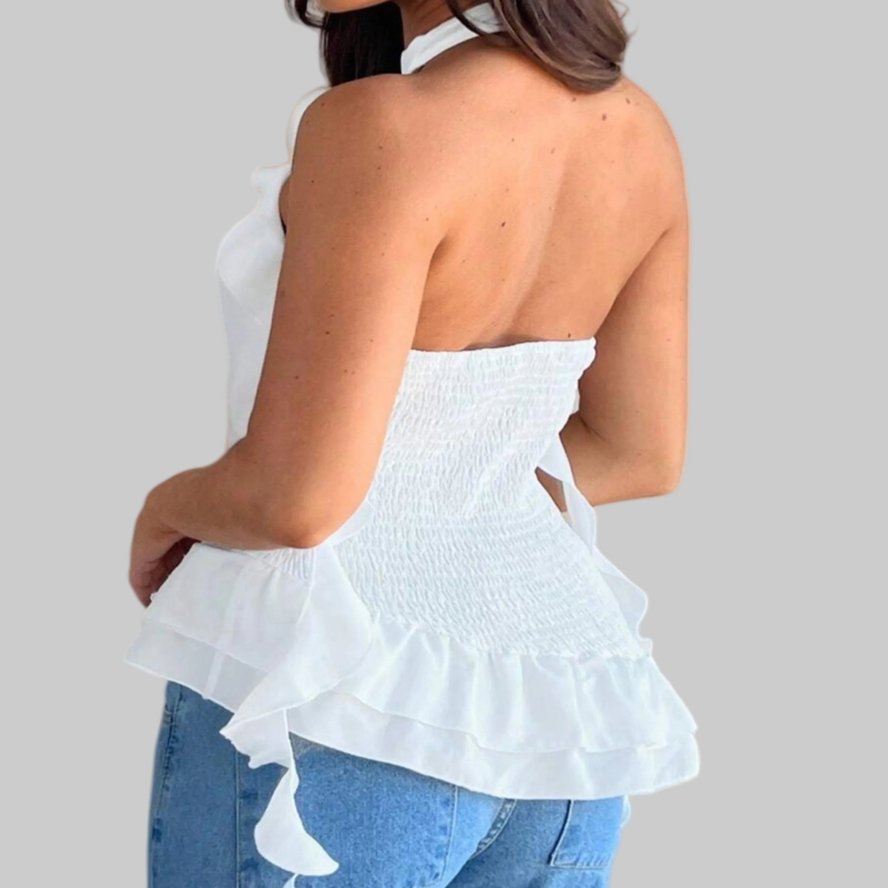 White strapless top with ruffled details worn by a person on a plain background