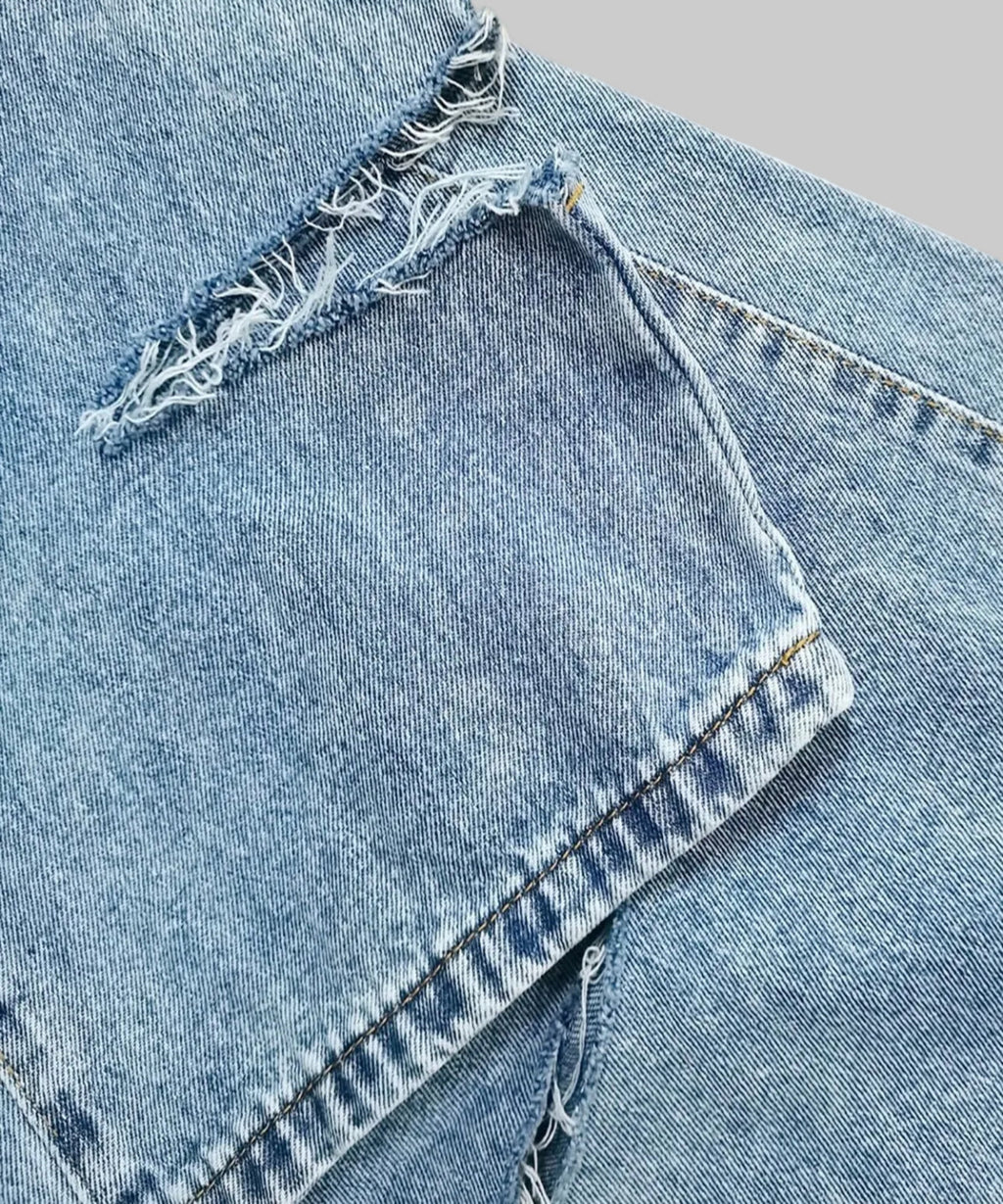 Close-up of blue denim jeans with frayed edges on a white background