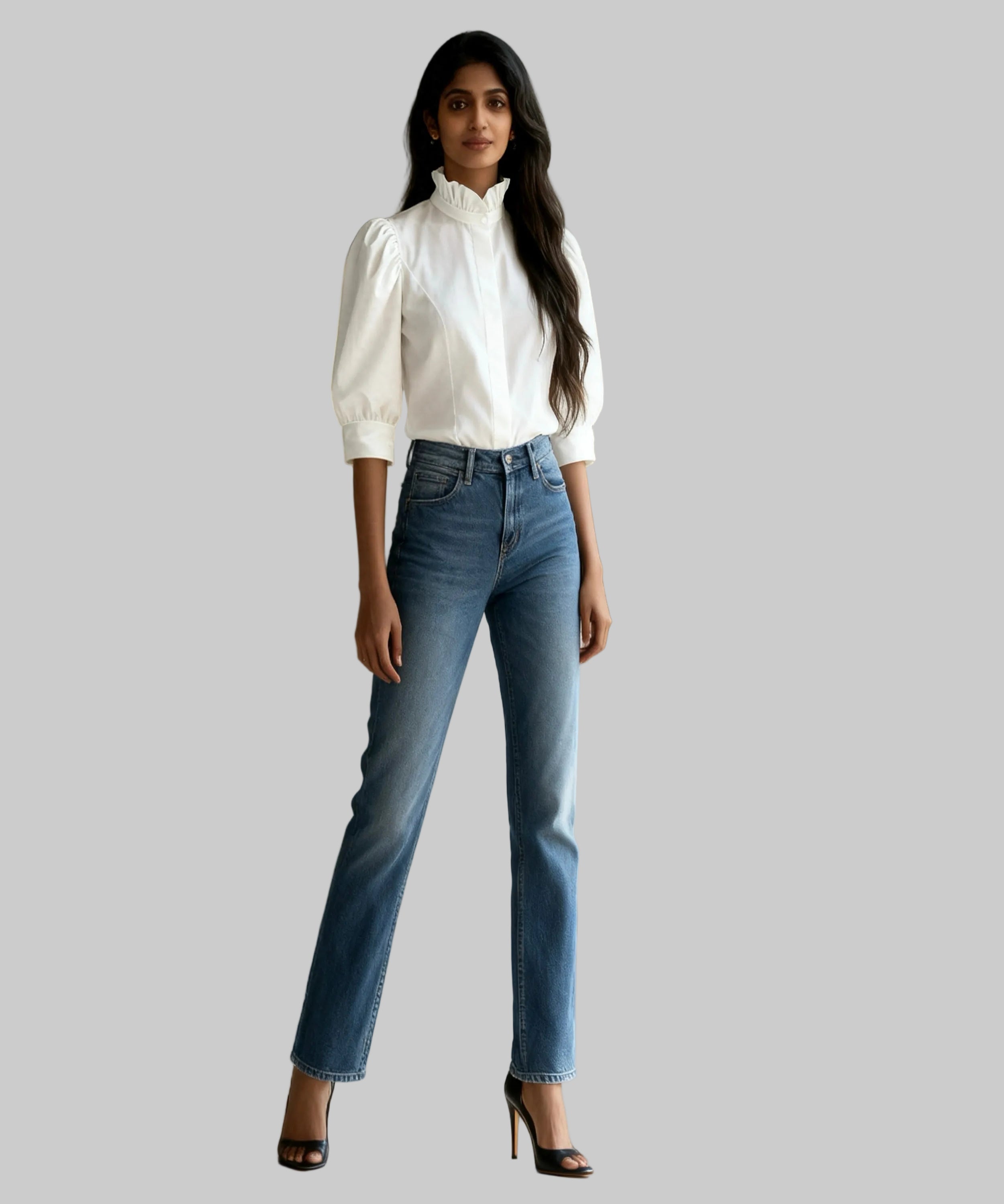Woman wearing a white blouse and blue jeans standing in a bright room.