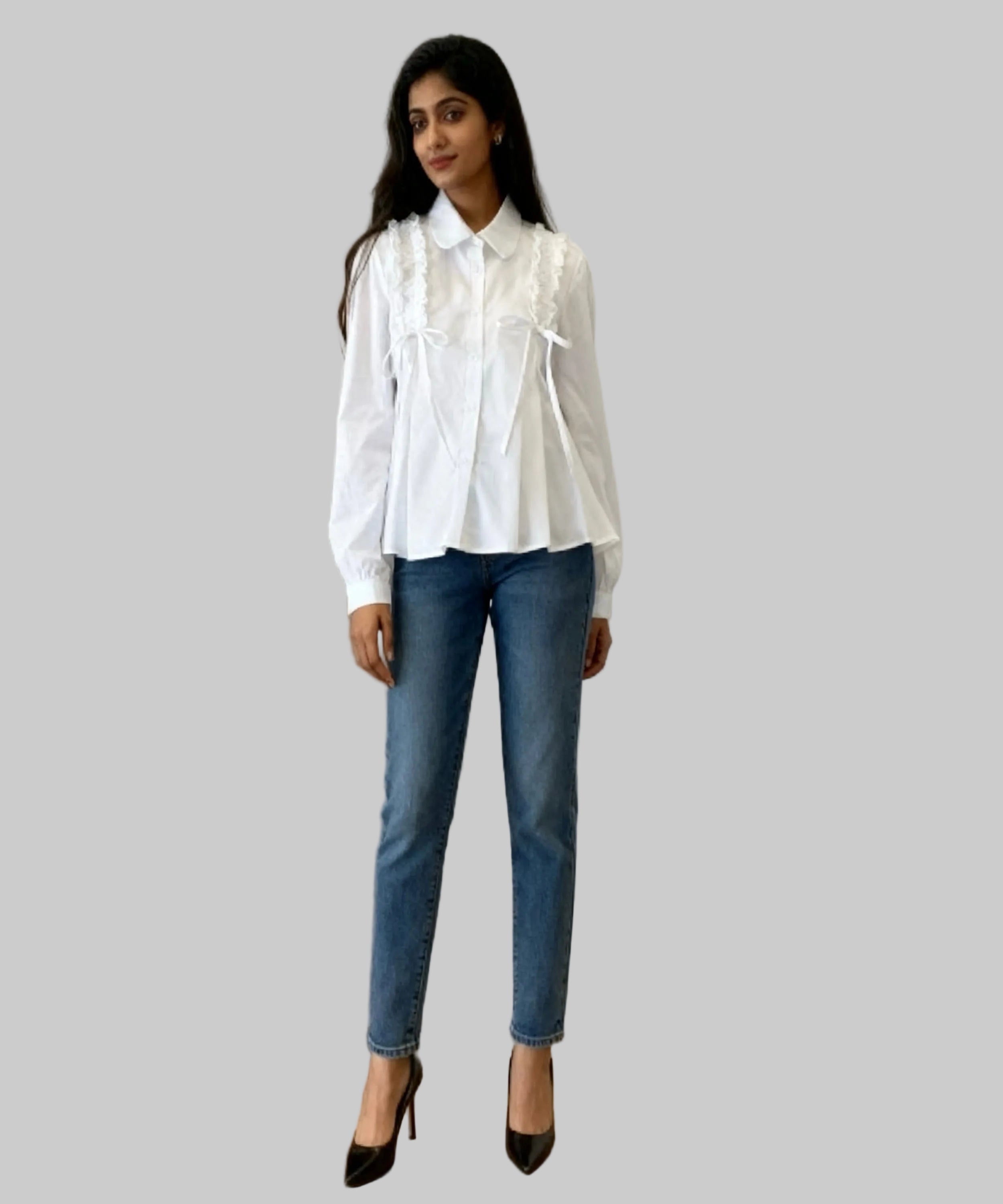Woman wearing a white blouse and blue jeans standing in a room with a black dresser.
