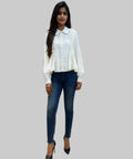 Woman wearing a white blouse and blue jeans standing in a clothing store.