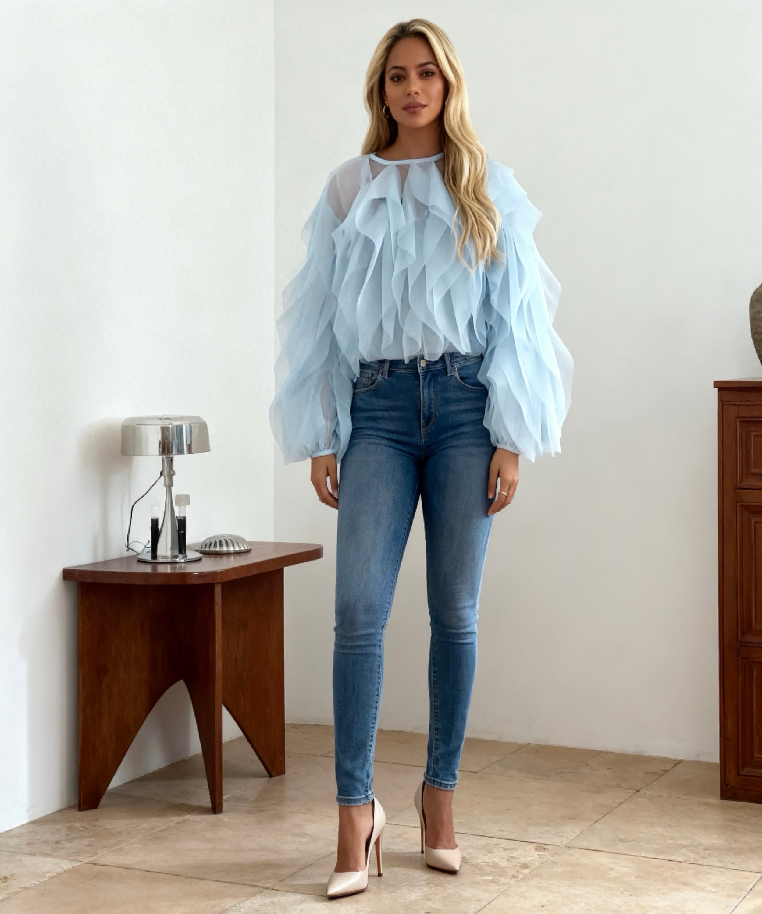 women wearing blue top, jeans and heels on a room background