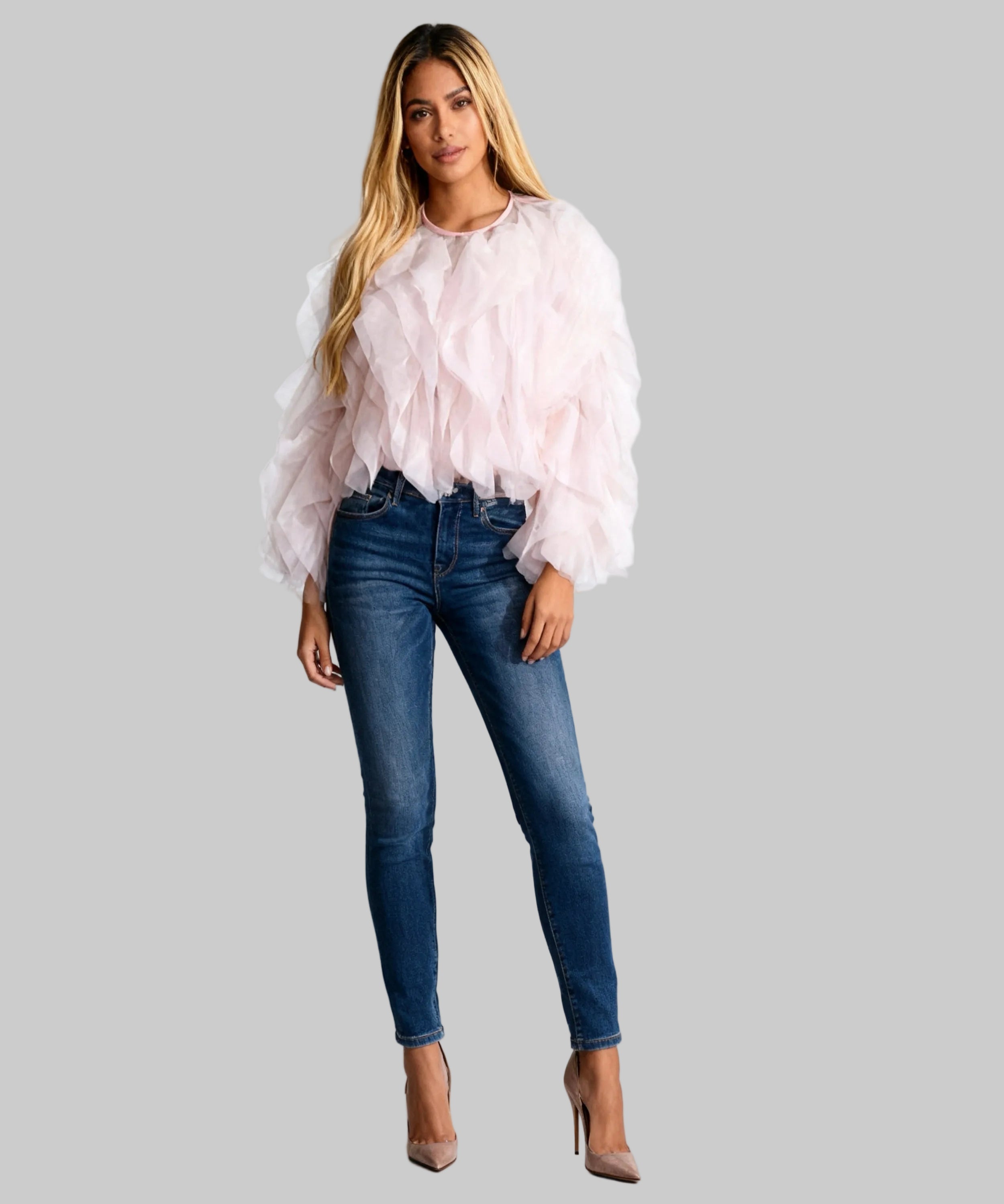 women dressed in a light pink top,jeans and heels on a white background