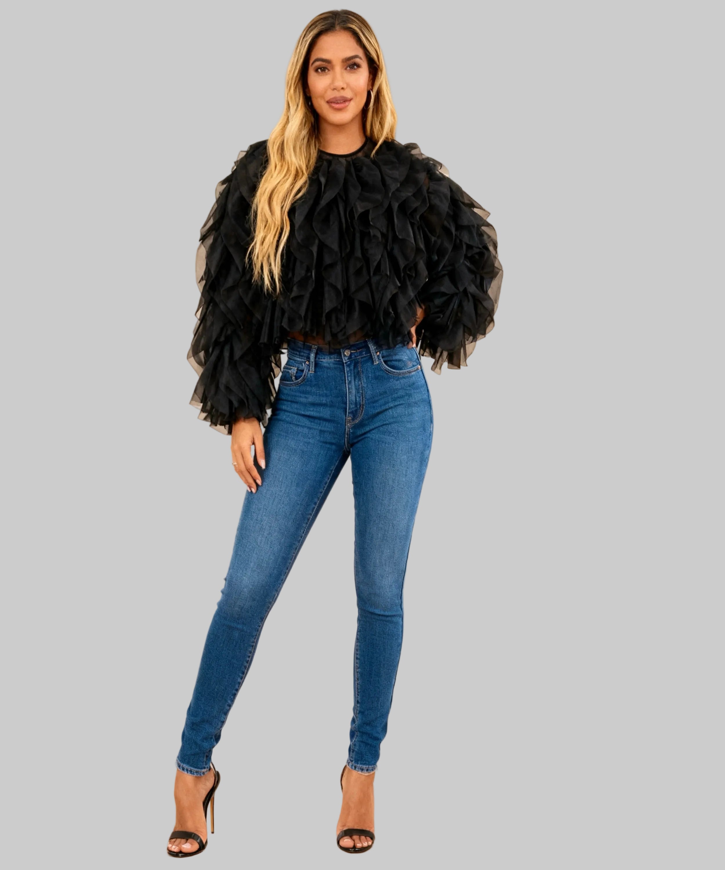 women dressed in a black top, jeans and heels on a white background

