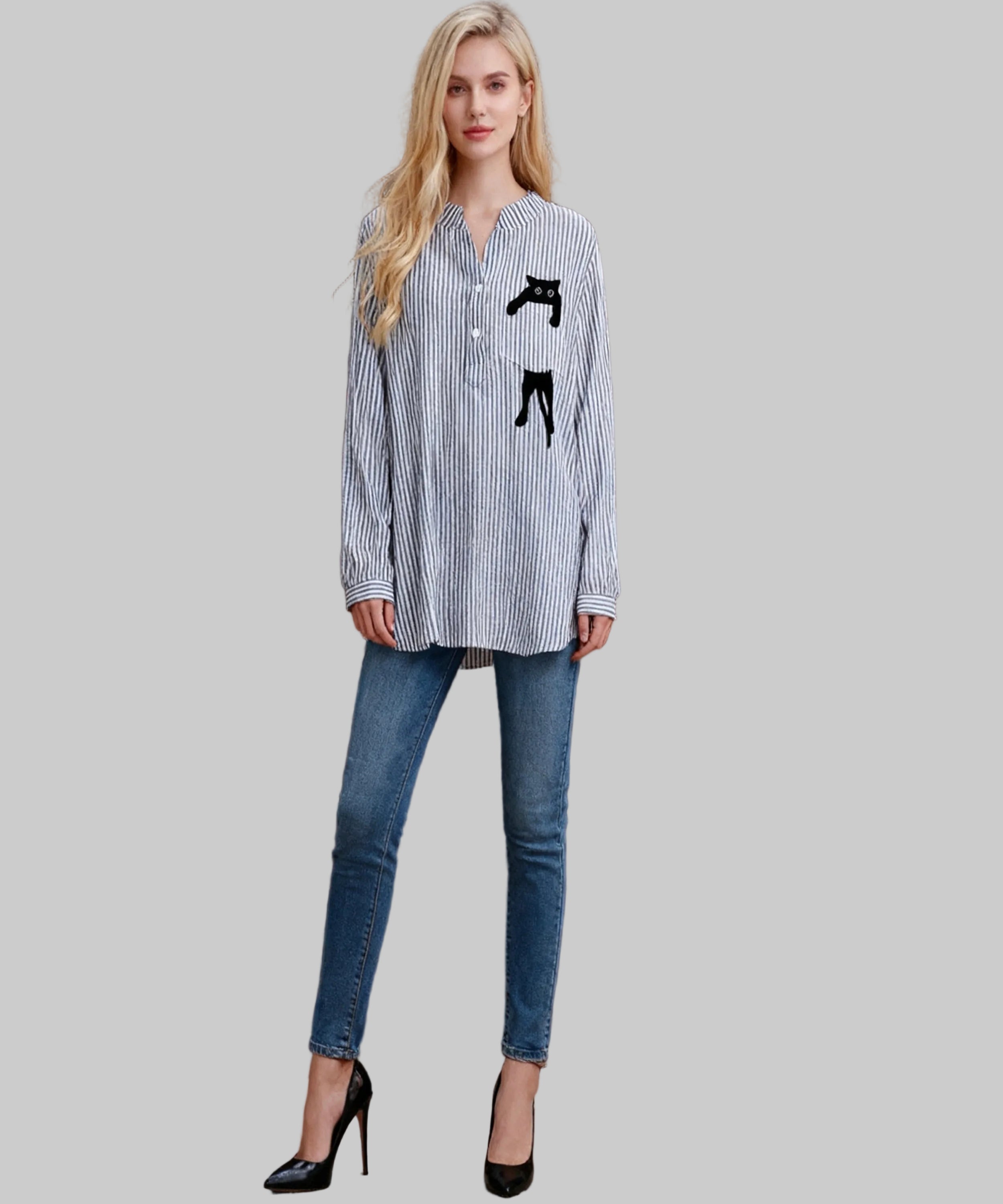 Woman wearing a striped shirt with a graphic design and jeans against a wooden background