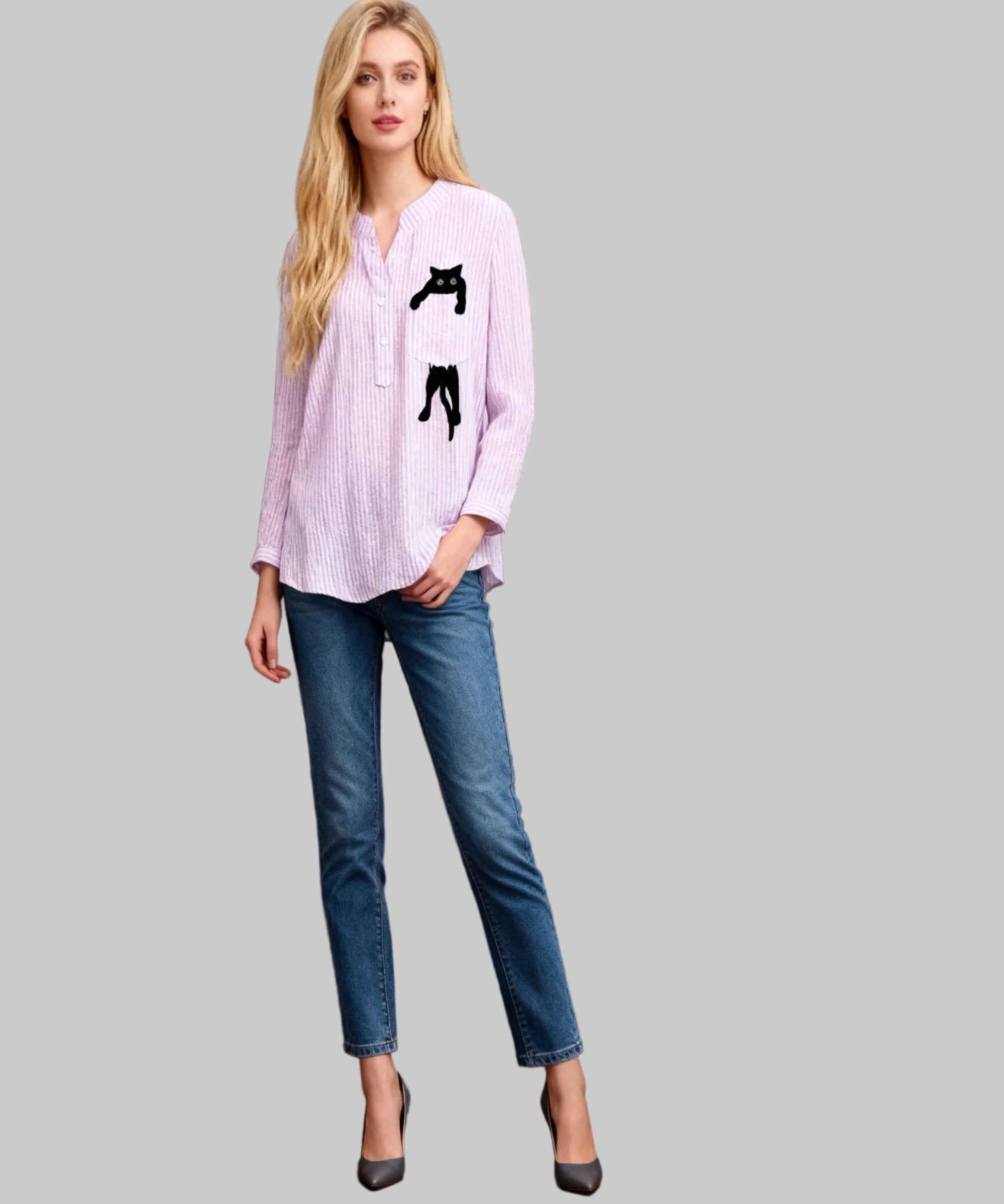 Woman wearing a light pink blouse with a black cat design and blue jeans against a wooden background