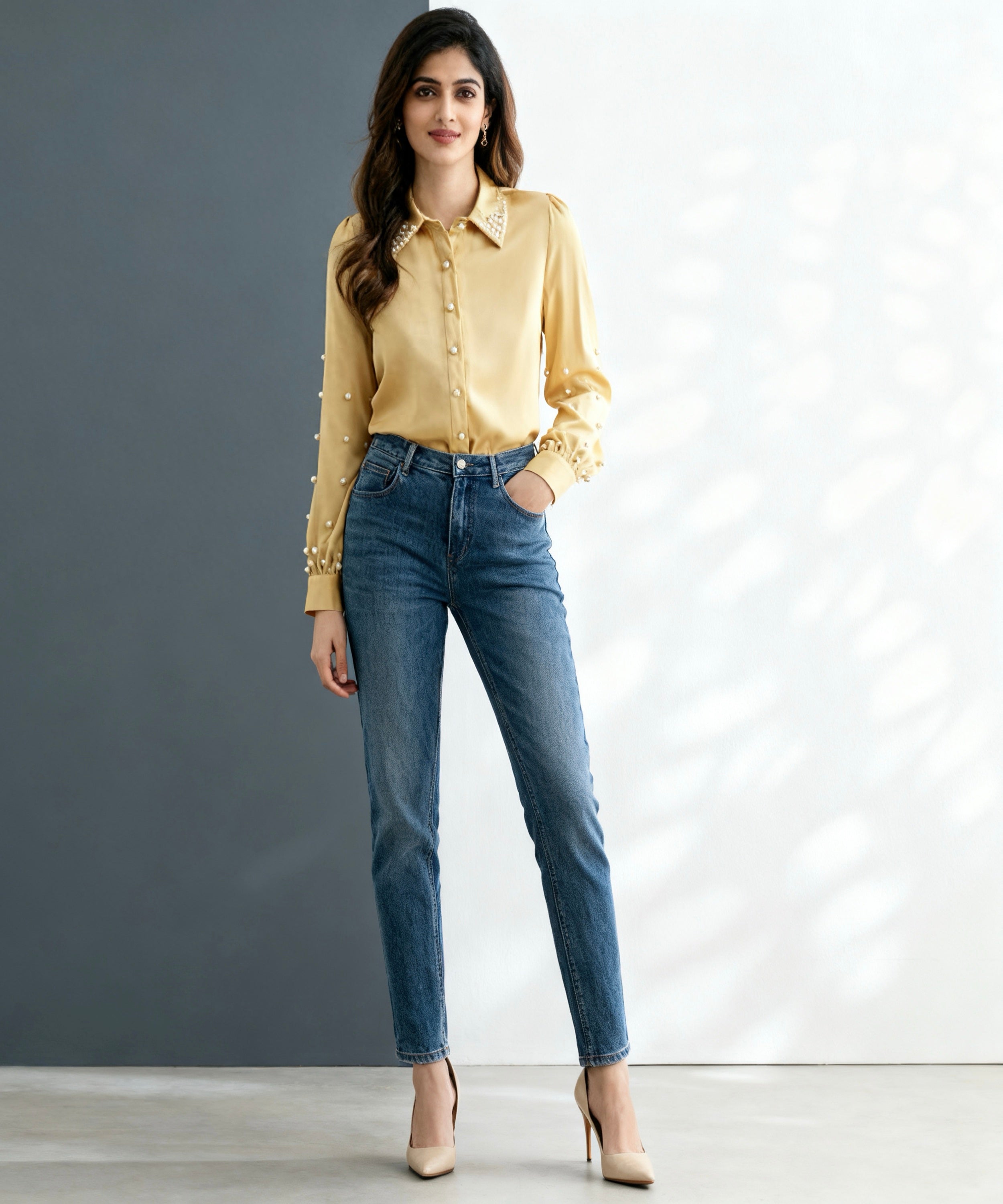 Woman wearing a yellow shirt and blue jeans against a gray background